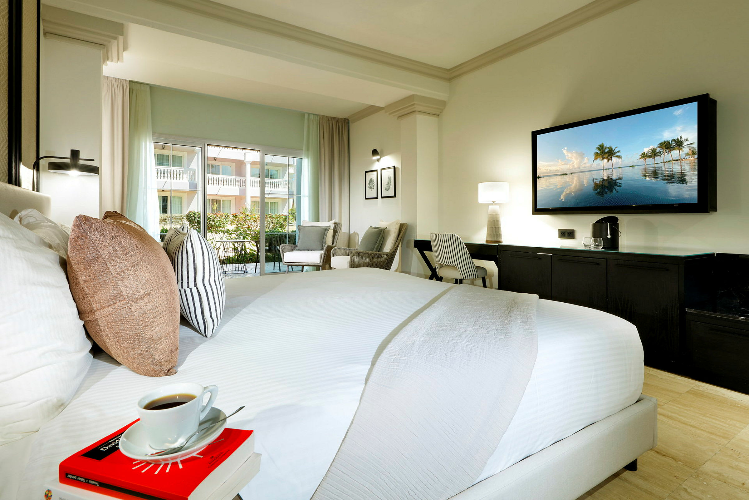 Hotelværelse med stor seng, siddeområde, skrivebord og TV på væggen. (AI-genereret tekst)