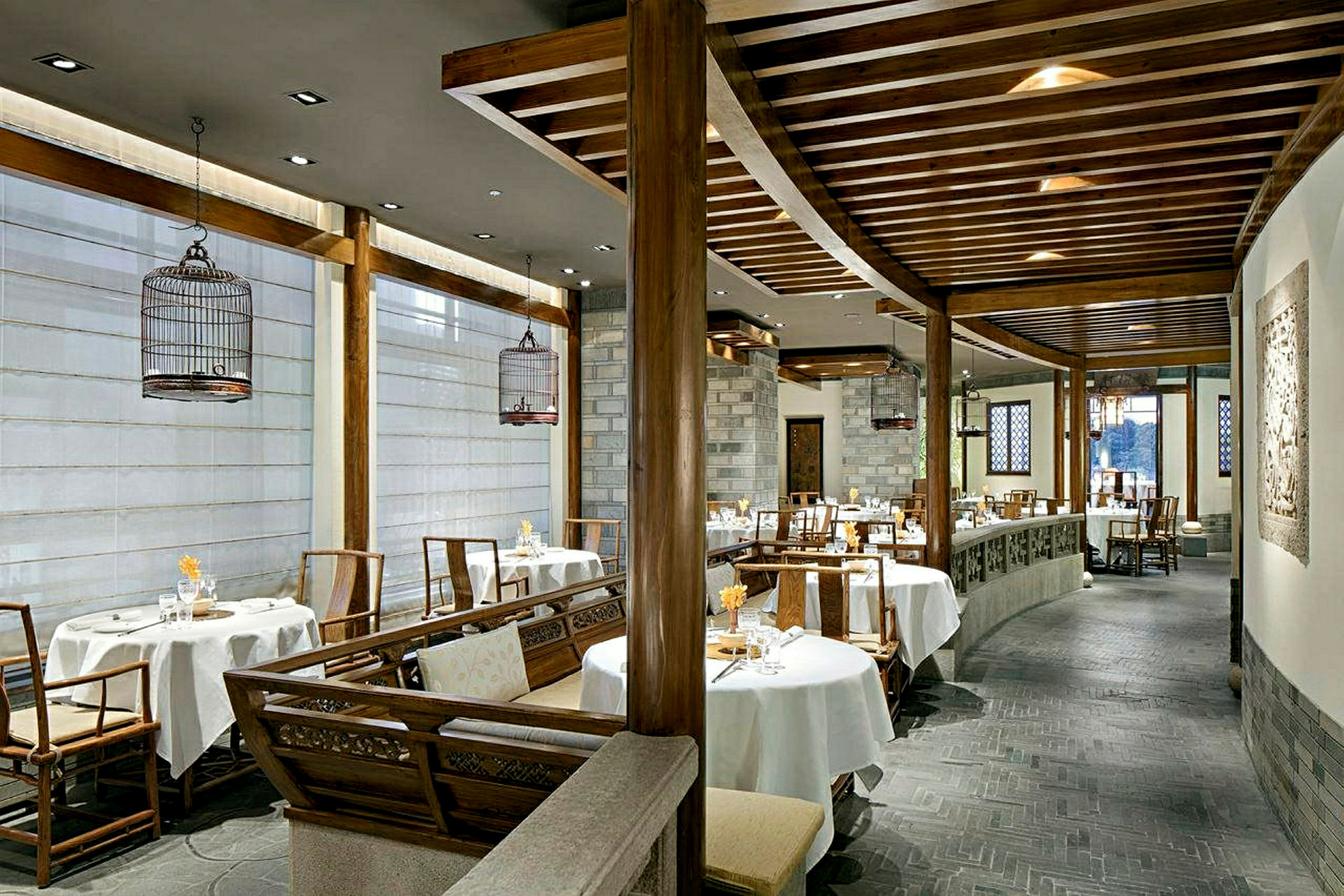 En elegant indrettet restaurant med runde borde og stole, hvide duge og træelementer i indretningen. (AI-genereret tekst)
