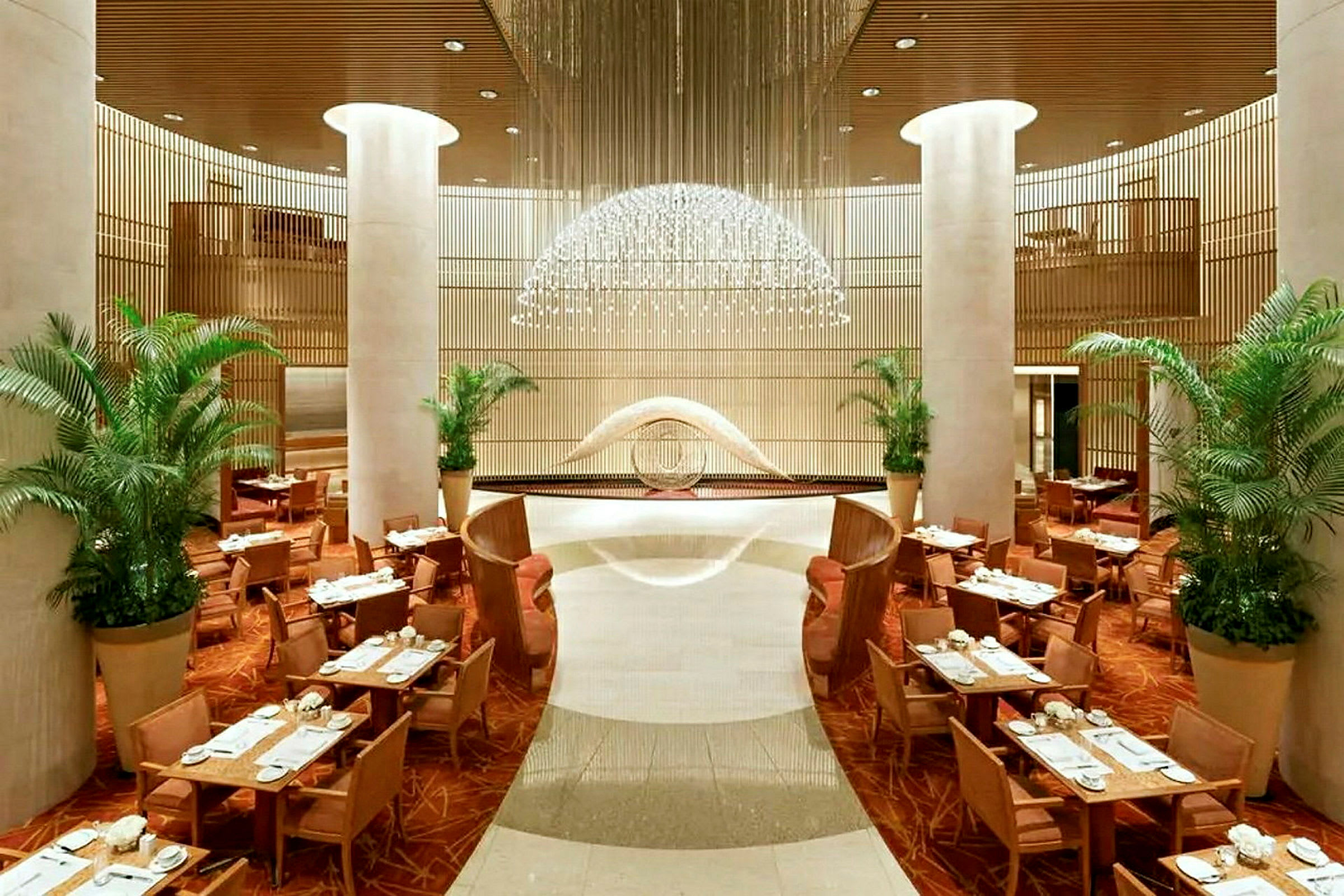 Et elegant restaurantområde med borde, stole og planter samt luksuriøs indretning. (AI-genereret tekst)