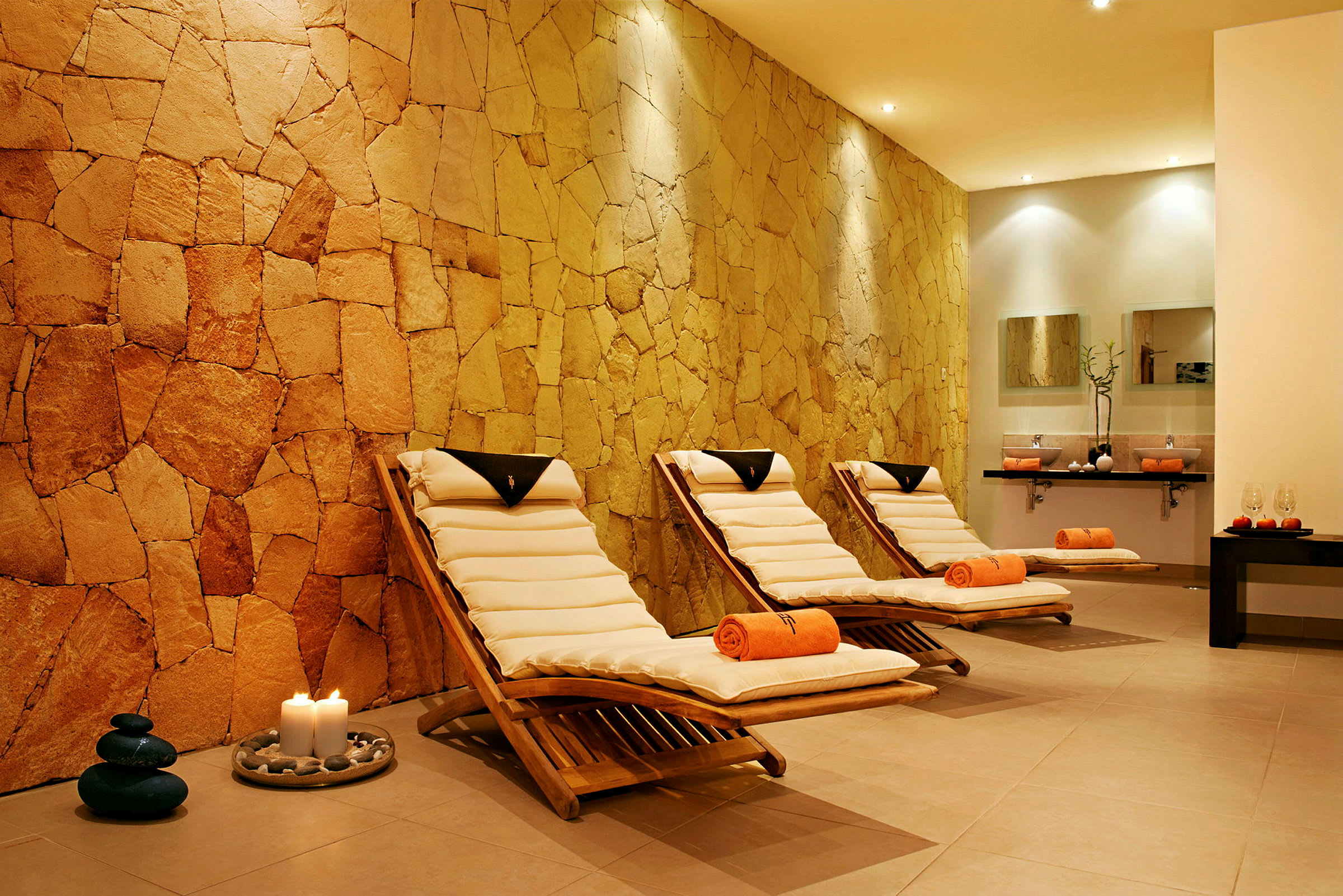 Spa-rum med tre solsenge og en væg af natursten. (AI-genereret tekst)