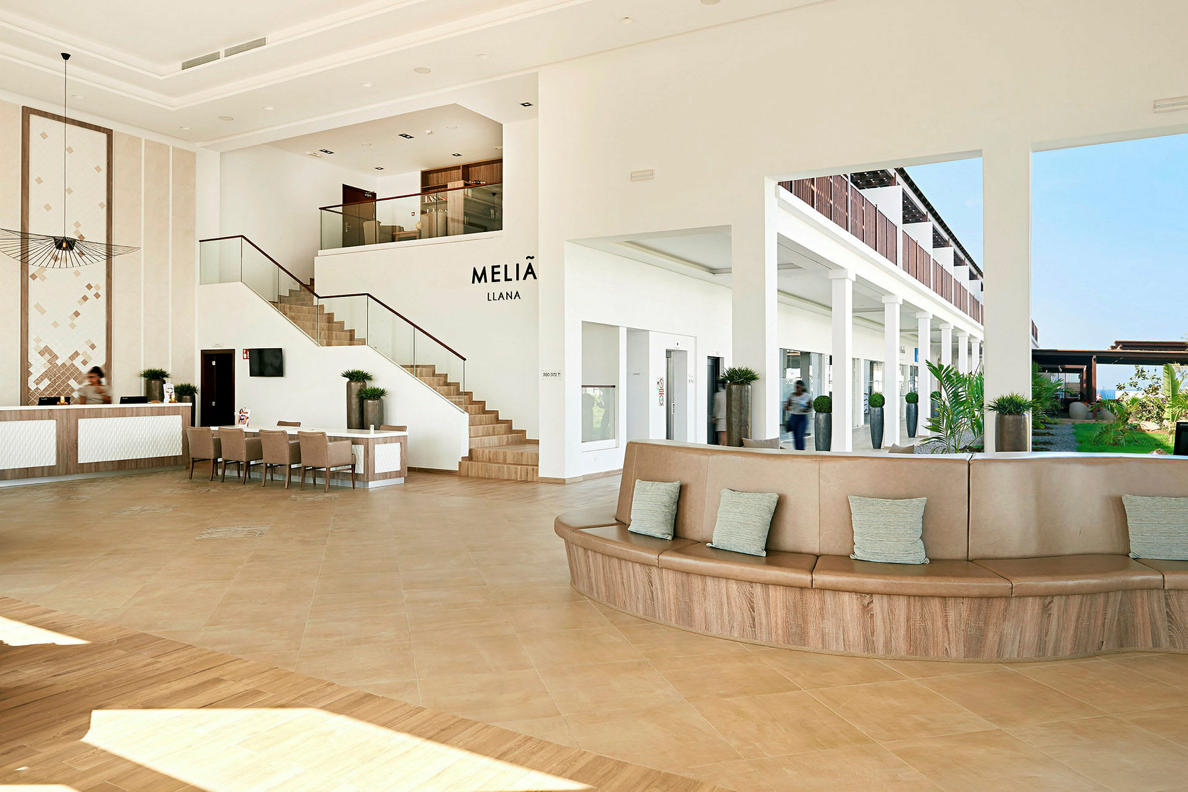 Moderne hotellets lobbyområde med reception, siddepladser og en trappe. (AI-genereret tekst)