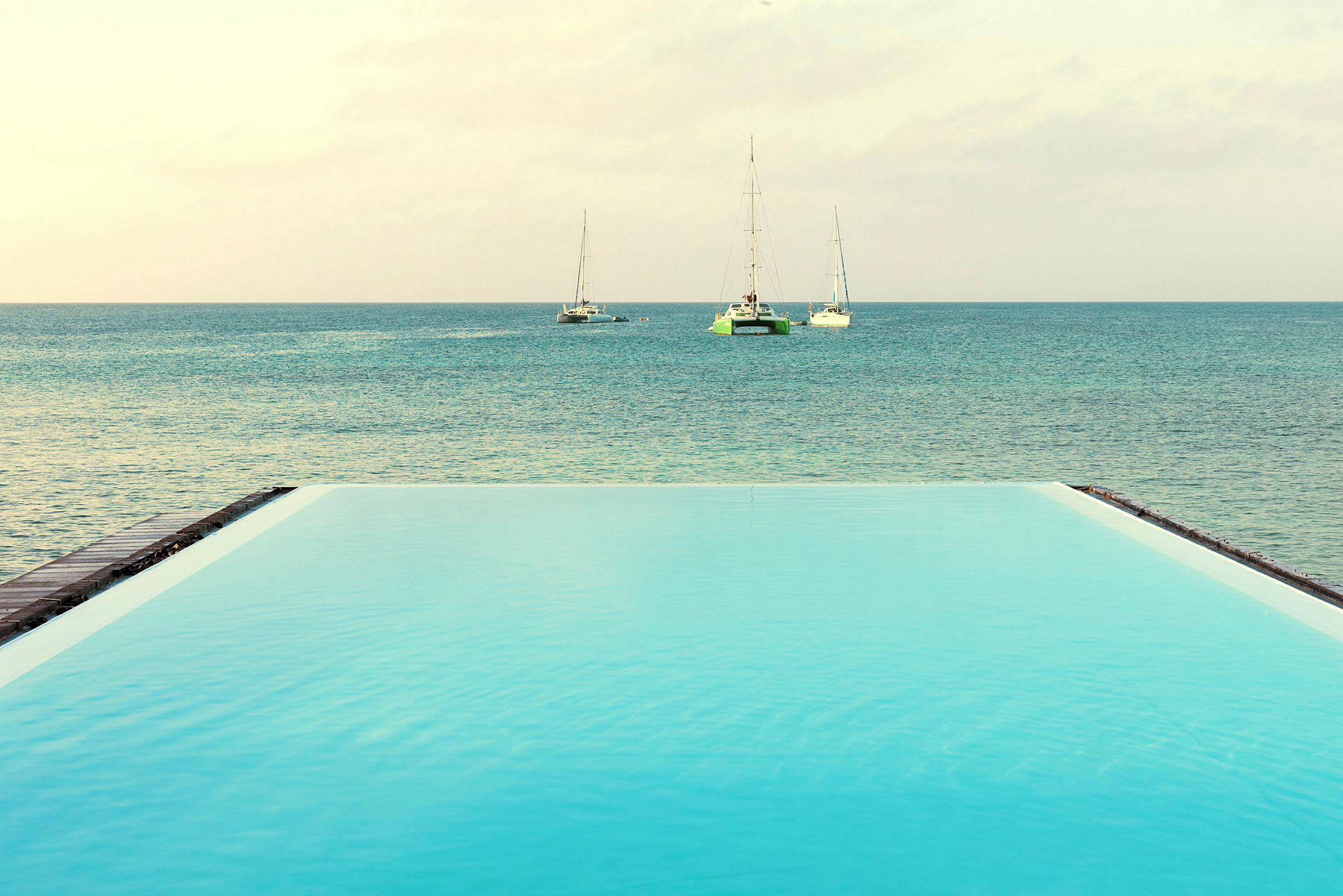 Infinitypool ved havet med sejlbåde i det fjerne. (AI-genereret tekst)