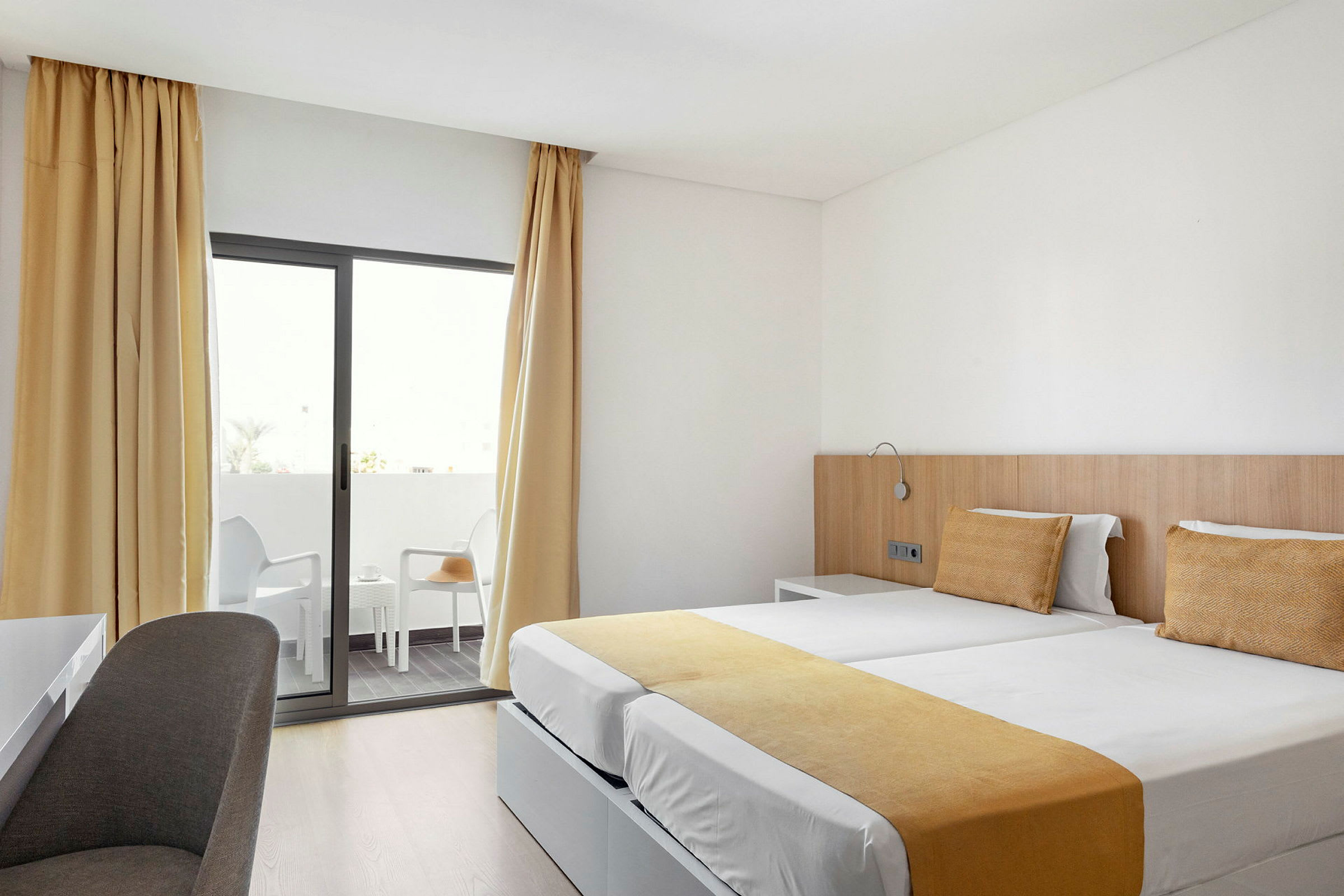 Hotelværelse med to enkeltsenge og altan. (AI-genereret tekst)