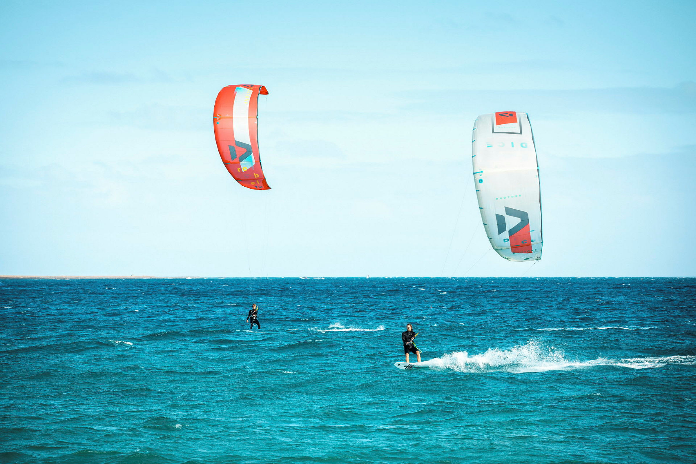 To personer kitesurfer på havet med farverige drager. (AI-genereret tekst)