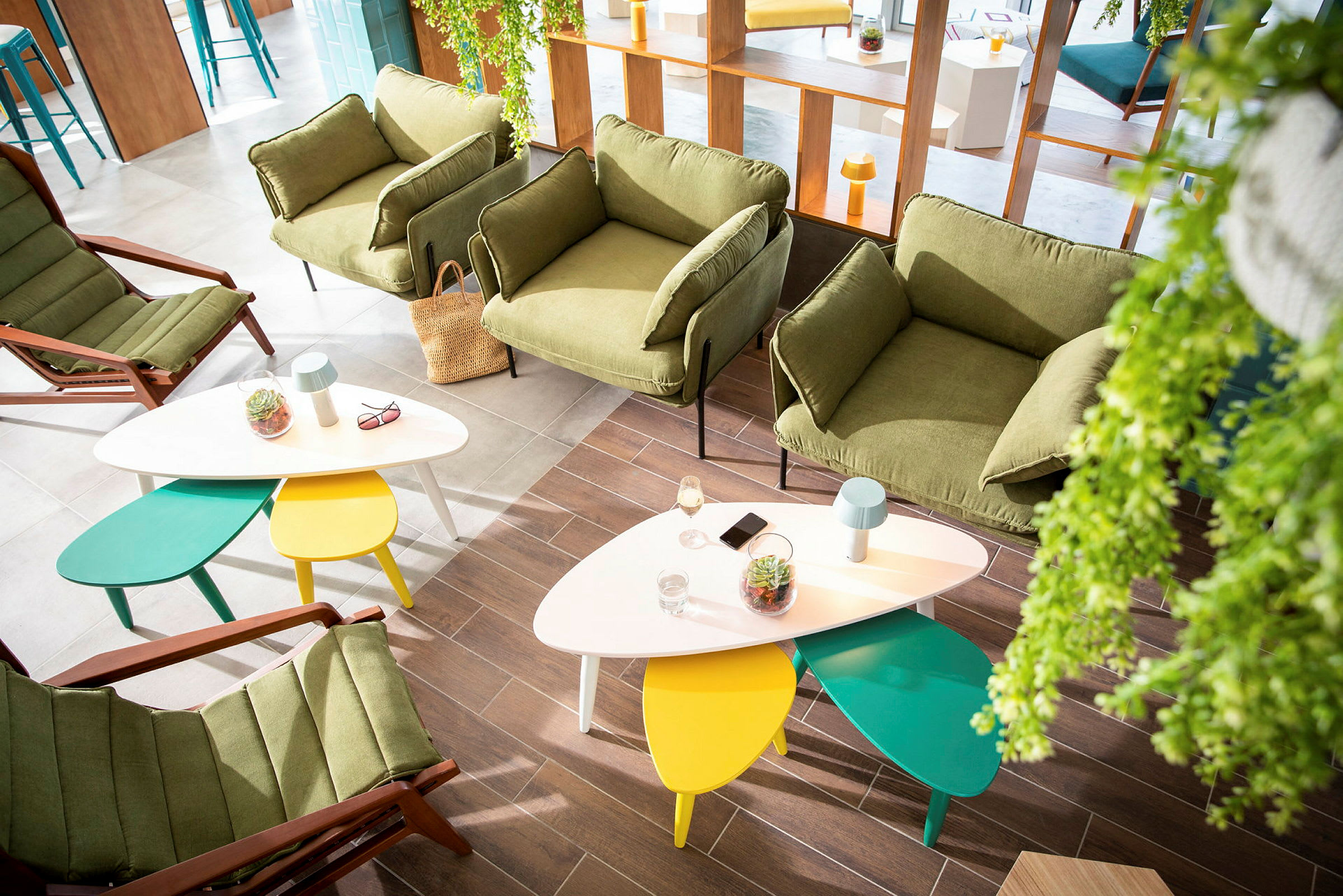 Moderne lounge med grønne lænestole og farverige borde. (AI-genereret tekst)