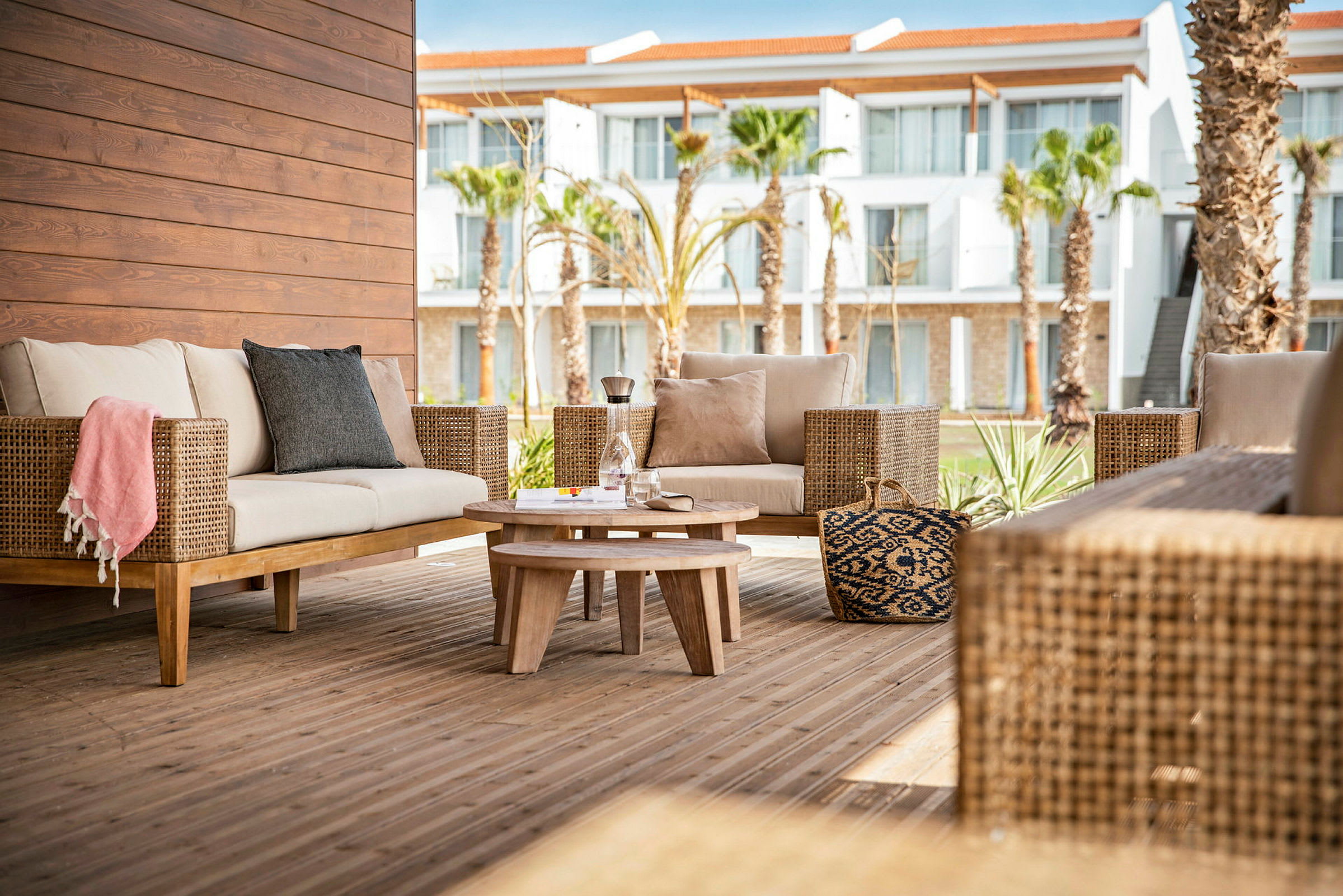 Udendørs loungeområde med kurvemøbler og et træbord på en terrasse. (AI-genereret tekst)