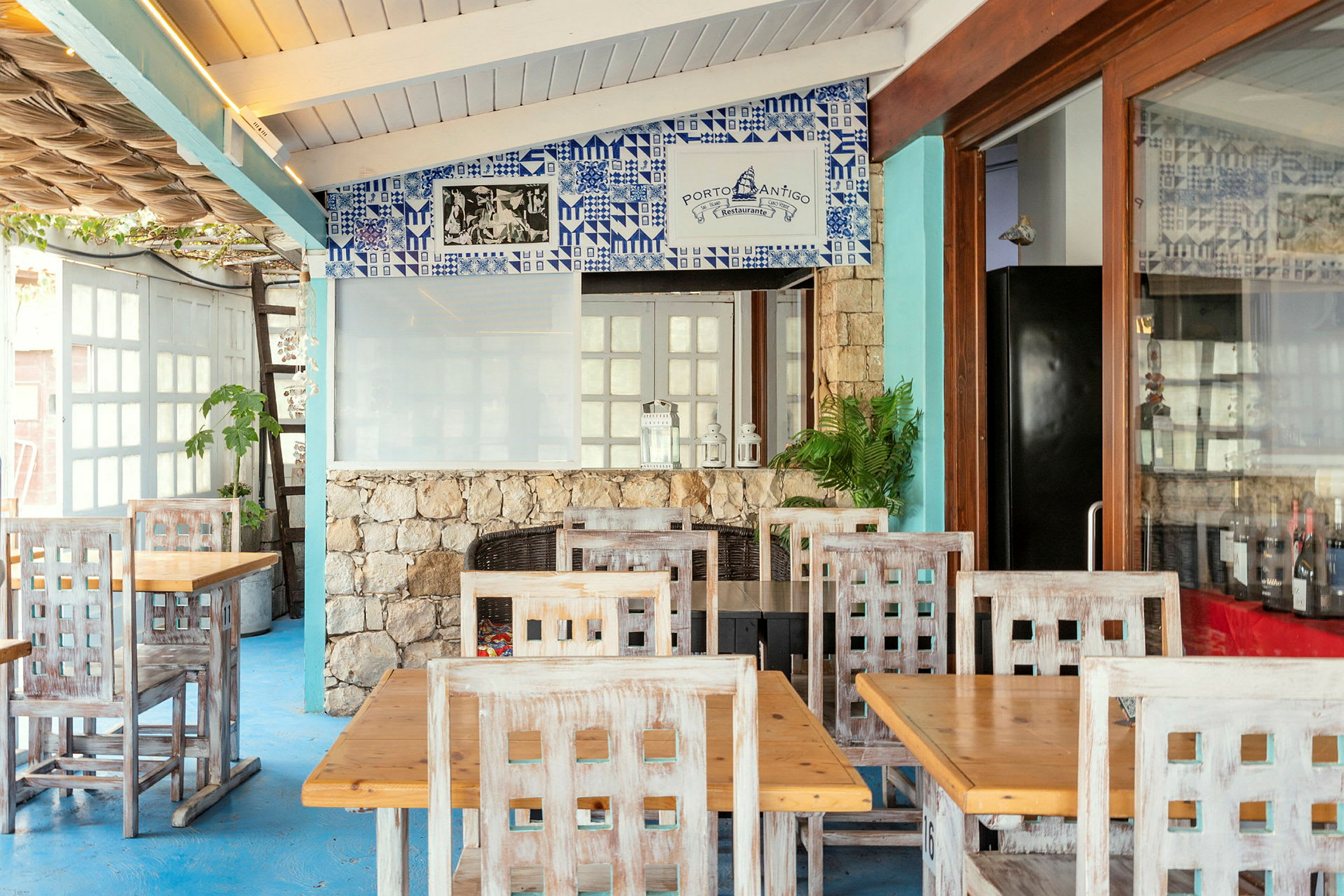 Restaurant med træborde og stole samt dekoreret væg med blå kakler. (AI-genereret tekst)