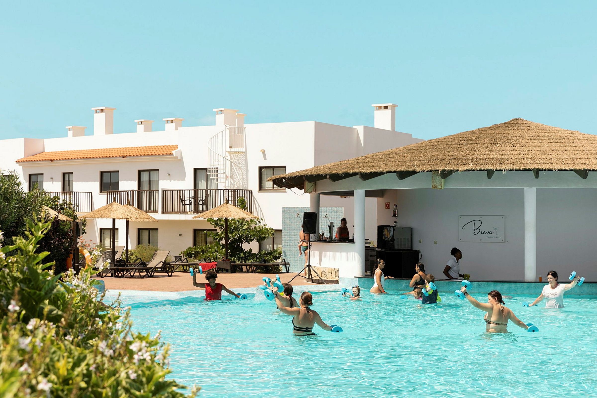 En gruppe mennesker anvender swimmingpoolen ved et hotelområde. (AI-genereret tekst)