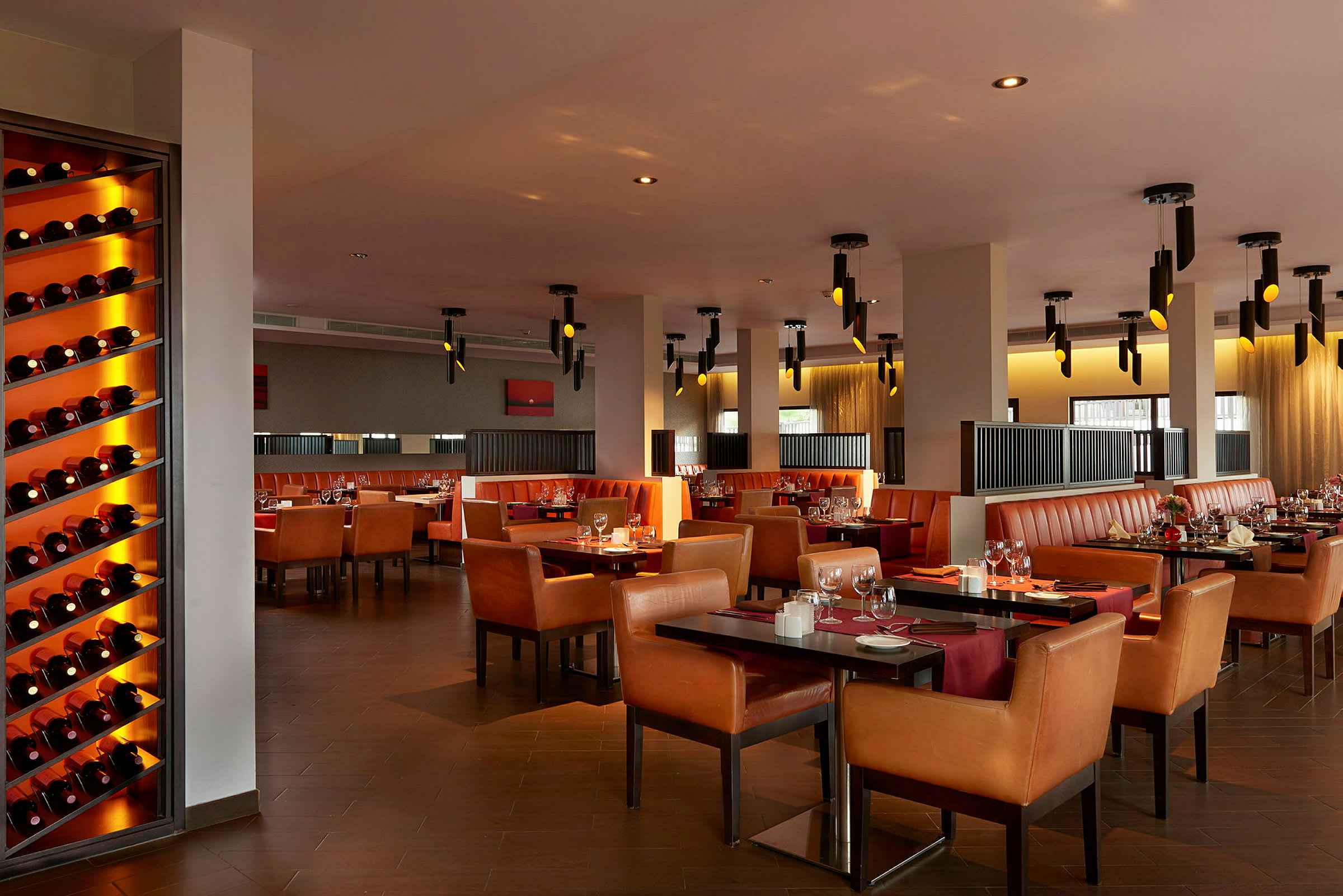En restaurant med flere borde, stole og vinflasker på en hylde. (AI-genereret tekst)