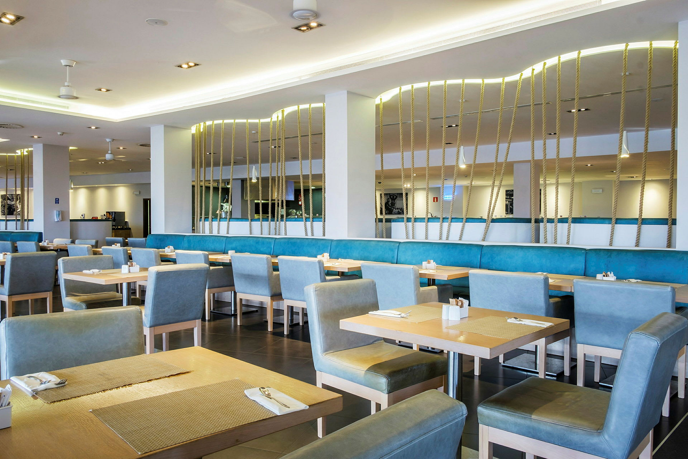 Interiør af en restaurant med borde og blå stole. (AI-genereret tekst)
