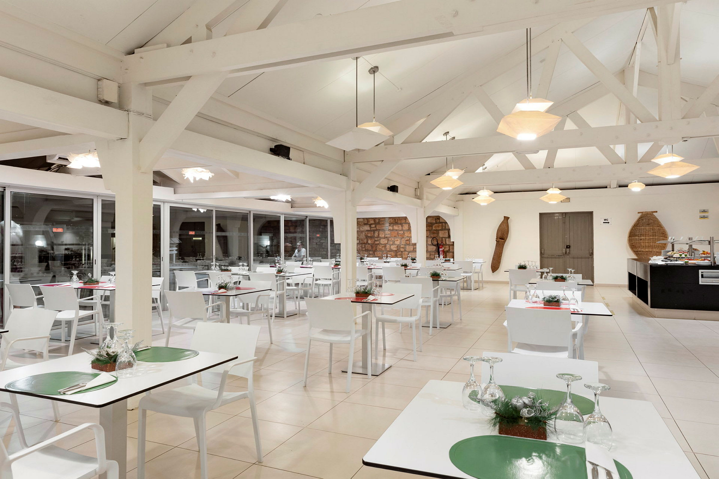 Et lyst restaurantområde med hvide borde og stole og moderne hængende lamper. (AI-genereret tekst)