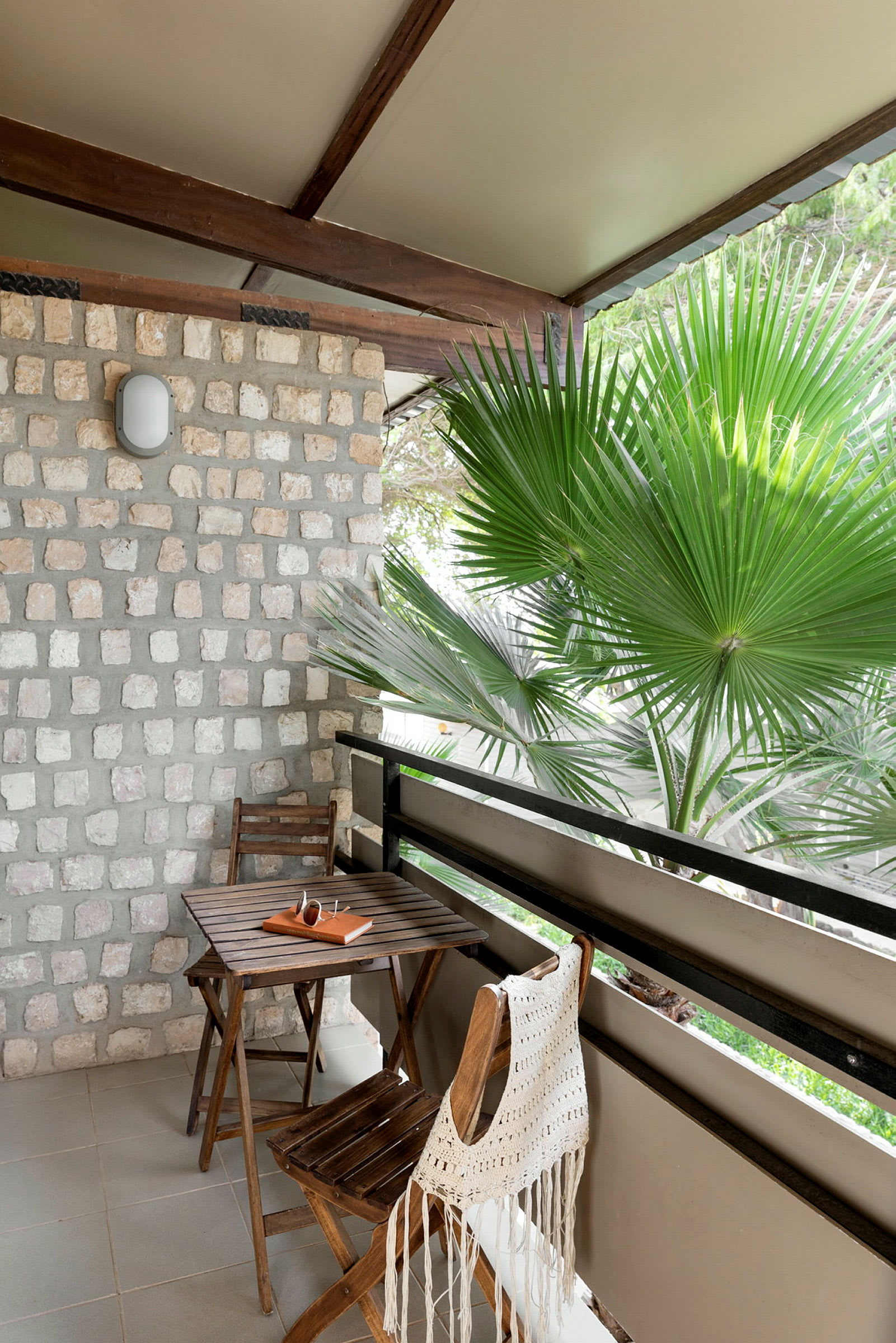 Et bord og to stole på en terrasse med udsigt til en palme. (AI-genereret tekst)
