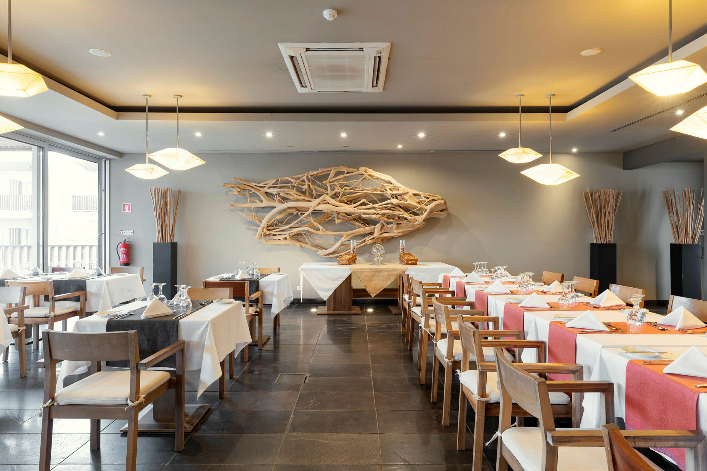 En restaurant med dækkede borde, dekorerede stole og trækunst på væggen. (AI-genereret tekst)