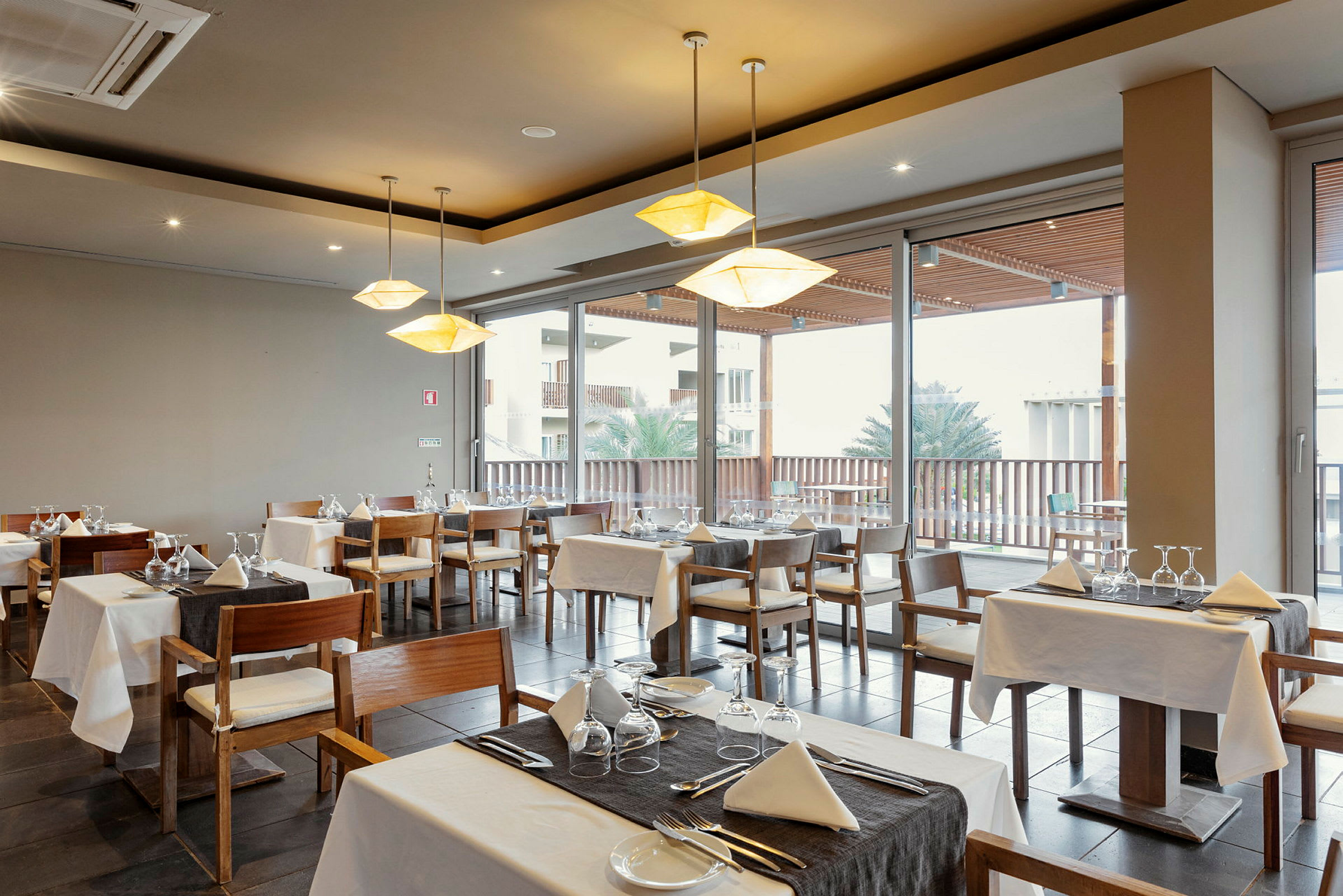 Restaurant med bord og stole nær store vinduer. (AI-genereret tekst)