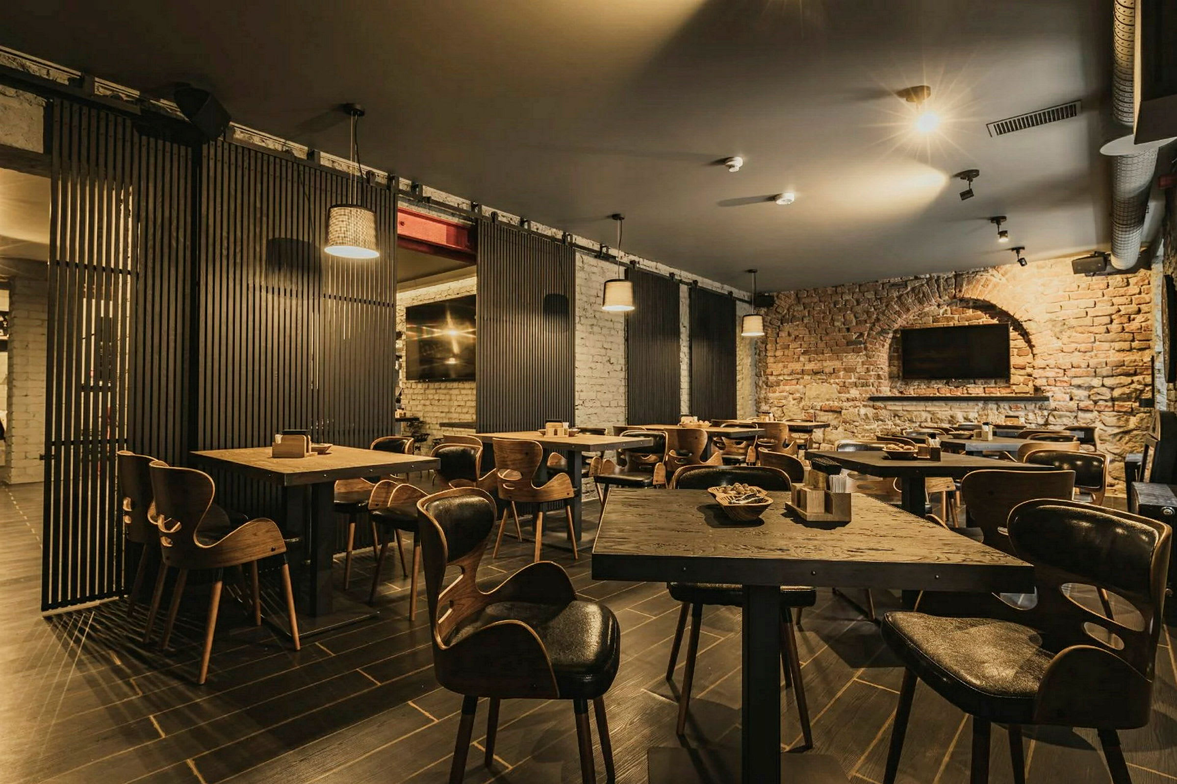 En restaurant med træborde og stole samt murstensvægge. (AI-genereret tekst)