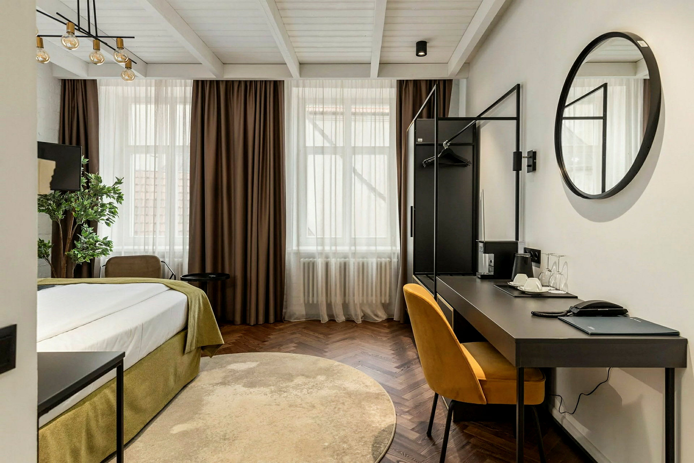 Et moderne hotelværelse med en seng, skrivebord og en gul stol. (AI-genereret tekst)