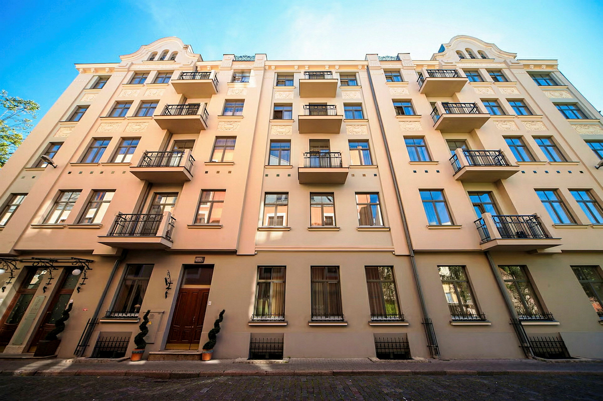 Facade af en beige bygning med flere altaner og blå vinduer. (AI-genereret tekst)