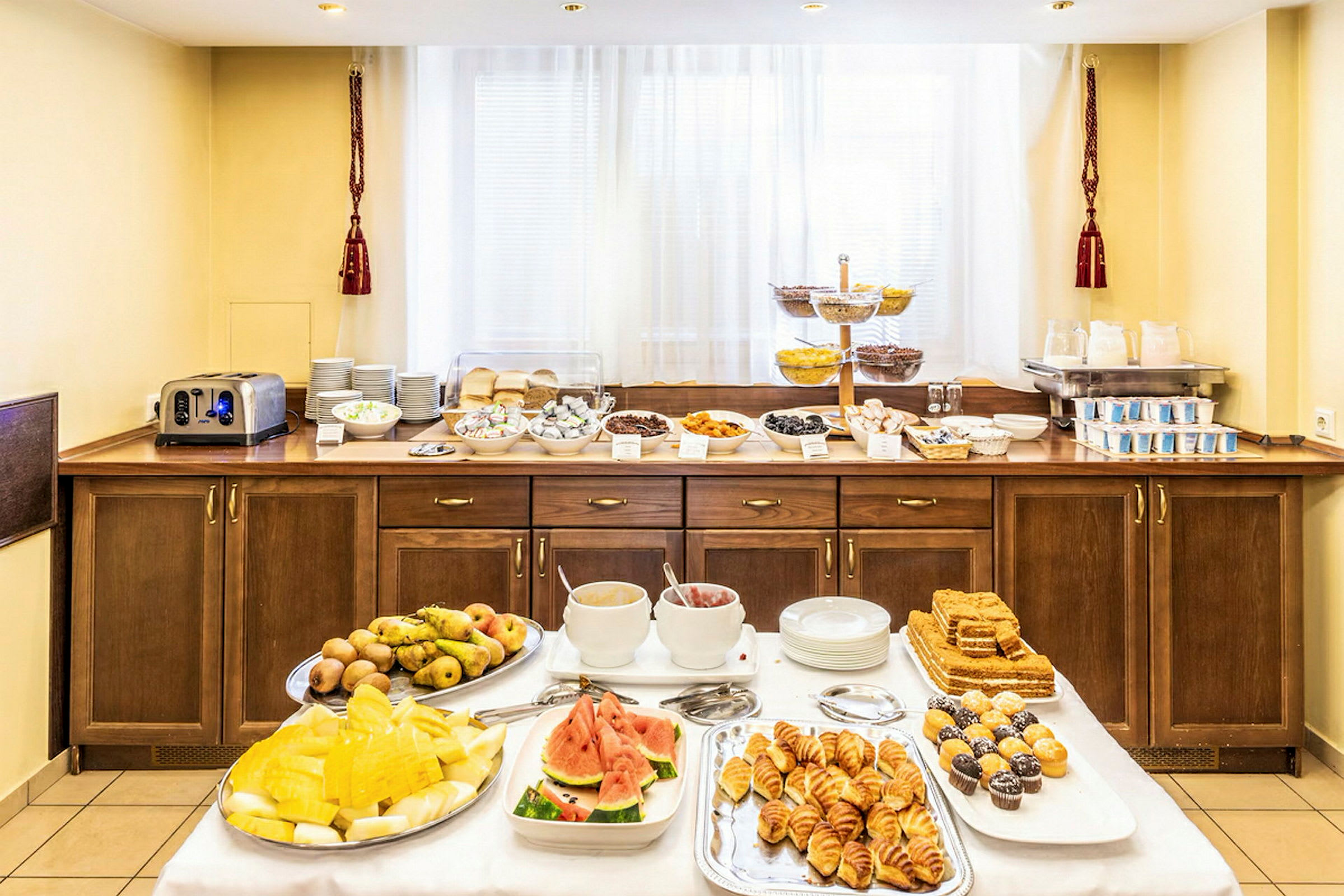 Hotelmorgenmadsbuffet med forskellige retter, herunder frugt, bagværk og drikkevarer. (AI-genereret tekst)