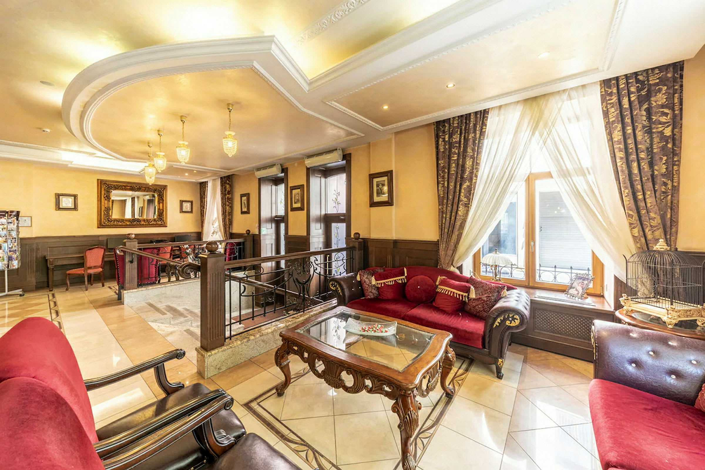 Lys og elegant hotellobby med røde sofaer og klassisk indretning. (AI-genereret tekst)