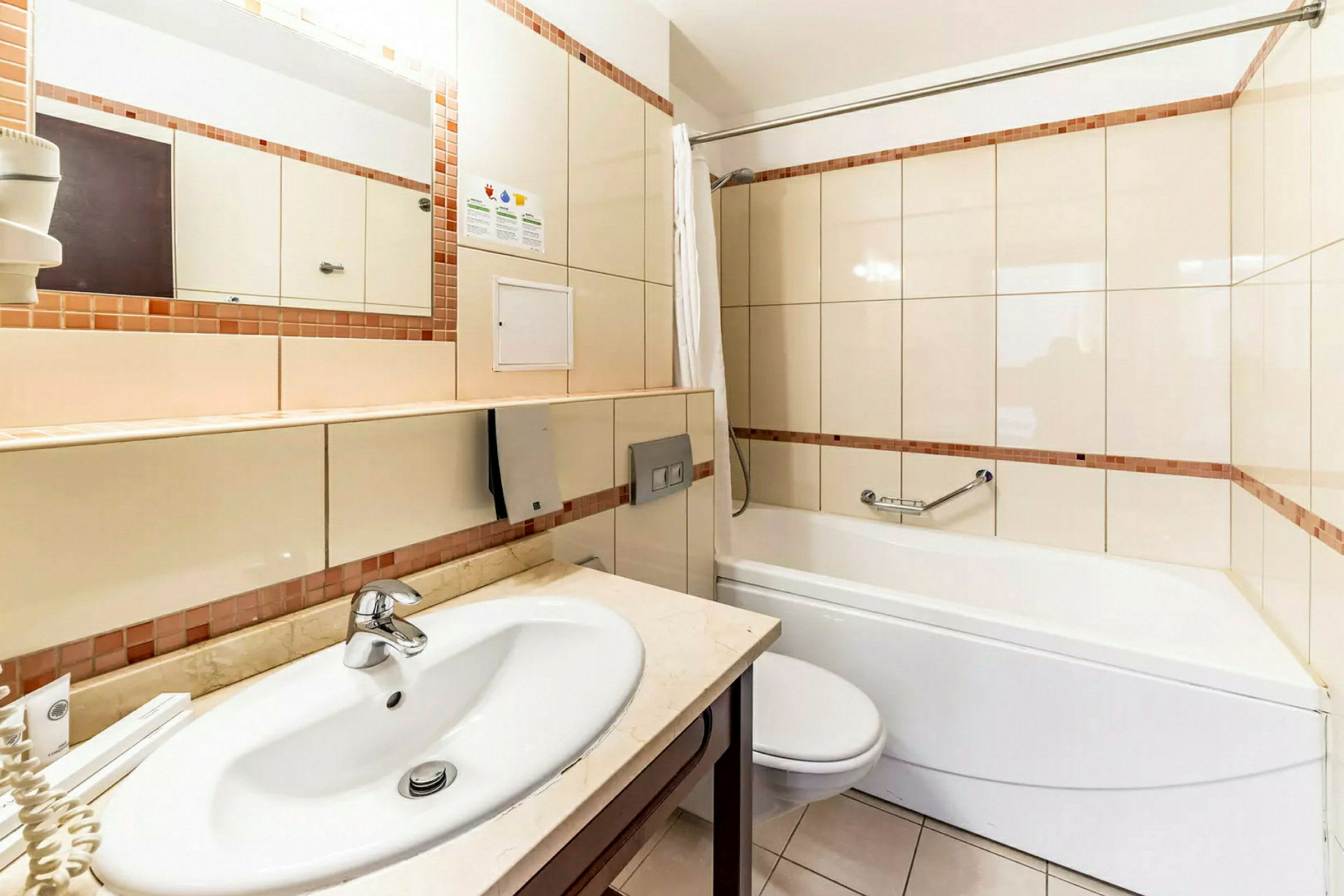 Et badeværelse med håndvask, toilet og badekar med bruser. (AI-genereret tekst)