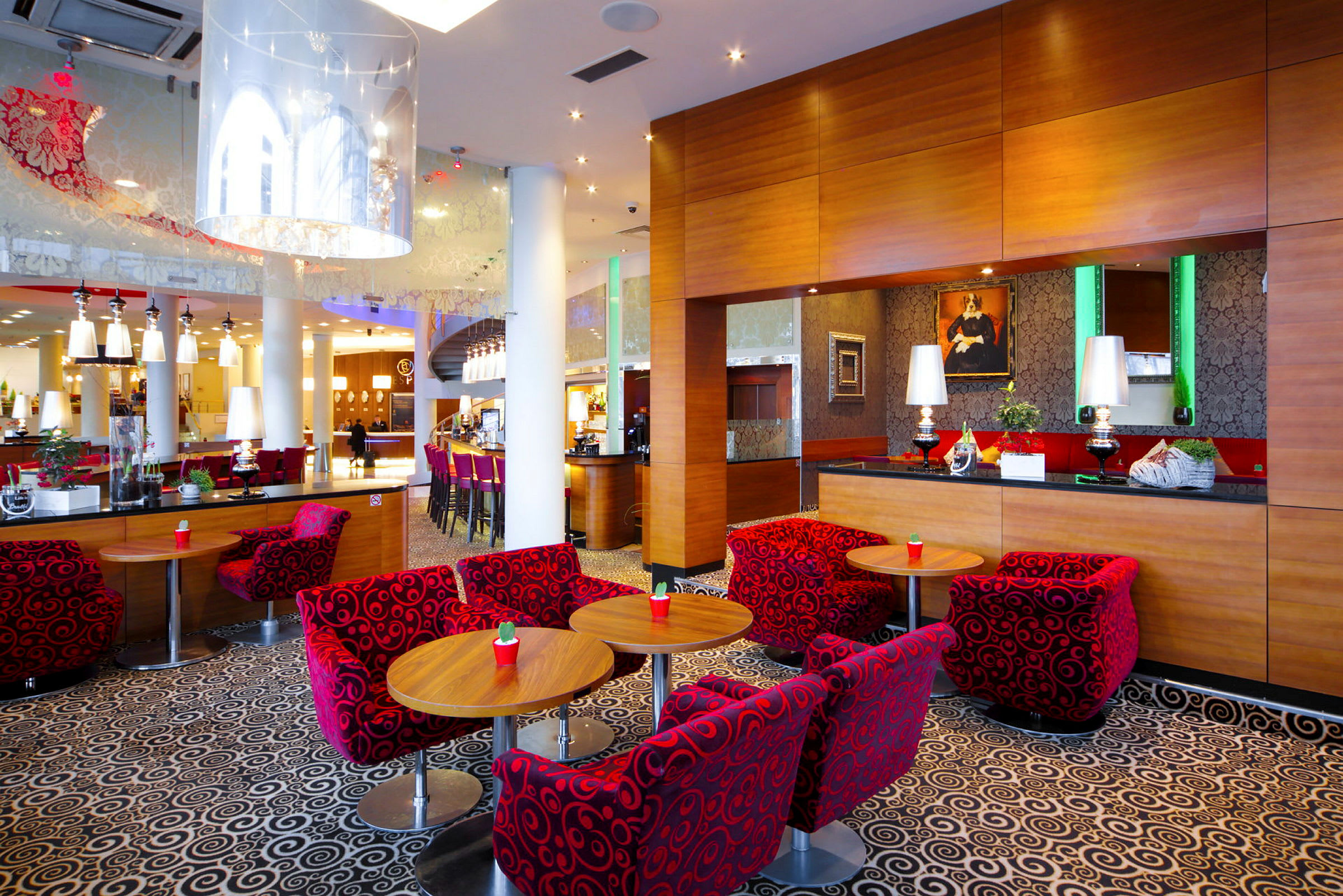 Dette er en moderne hotellobby med farverige møbler og en bar. (AI-genereret tekst)