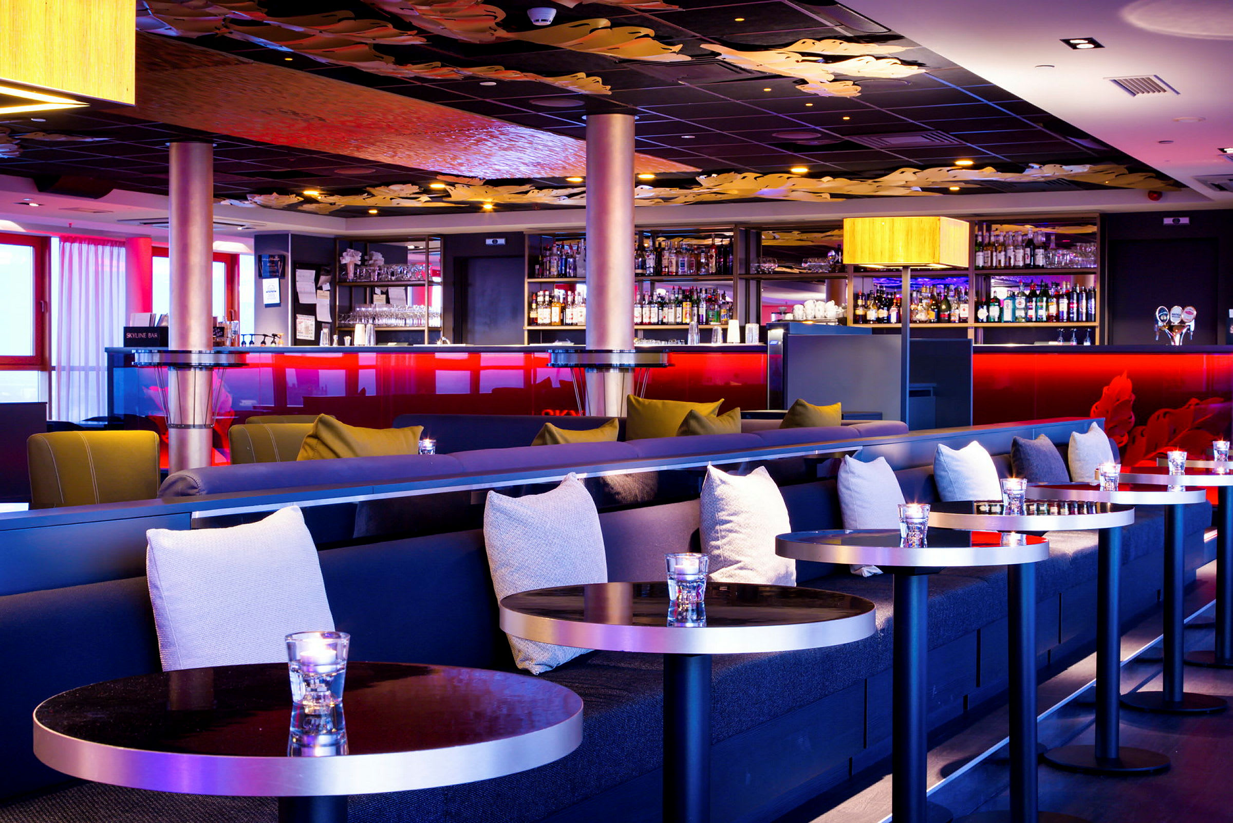 En elegant hotelbar med stilfuld indretning, komfortable sofaer og et veludstyret barskab. (AI-genereret tekst)