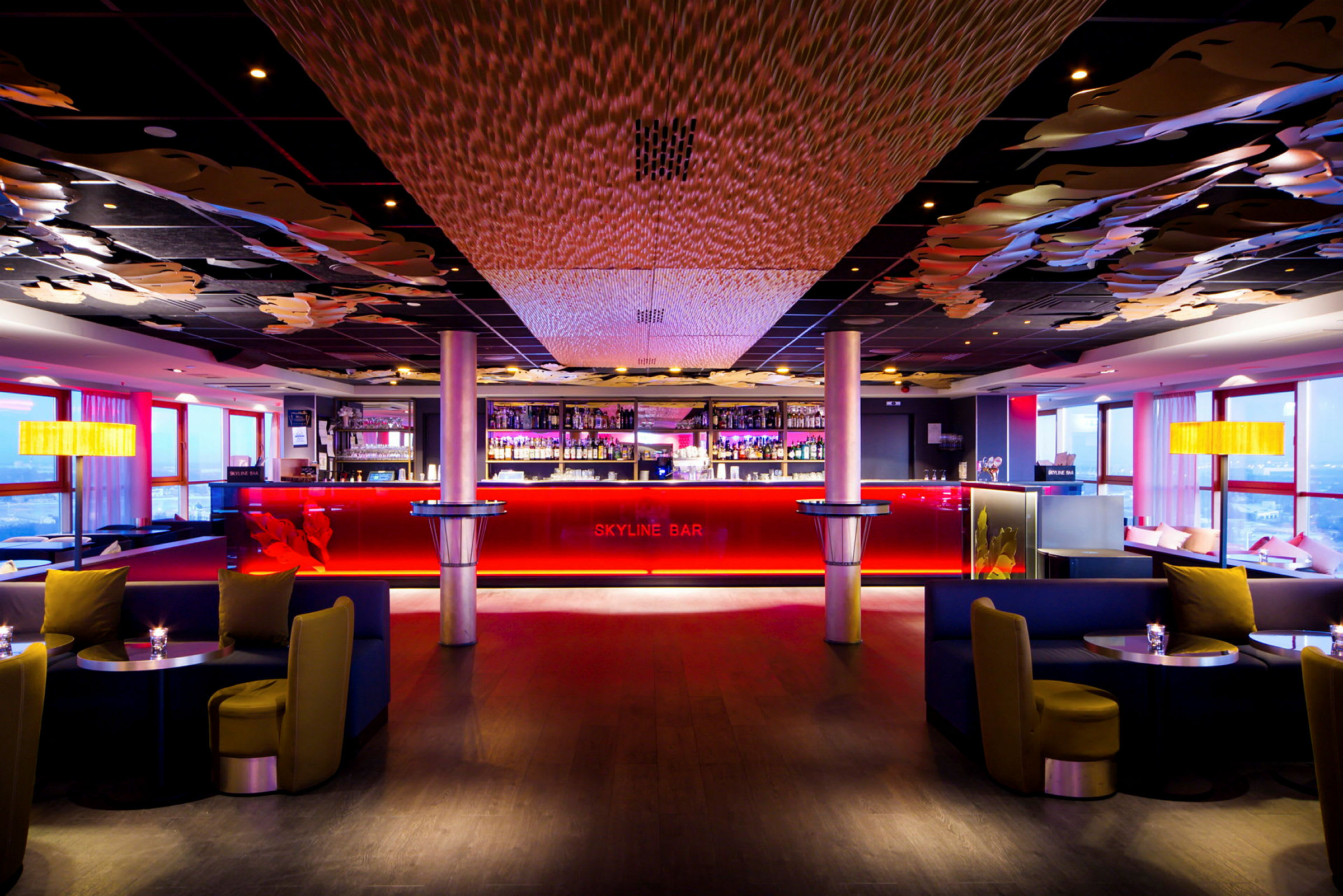 En elegant bar med rød belysning, mørke møbler og dekoreret loft. (AI-genereret tekst)
