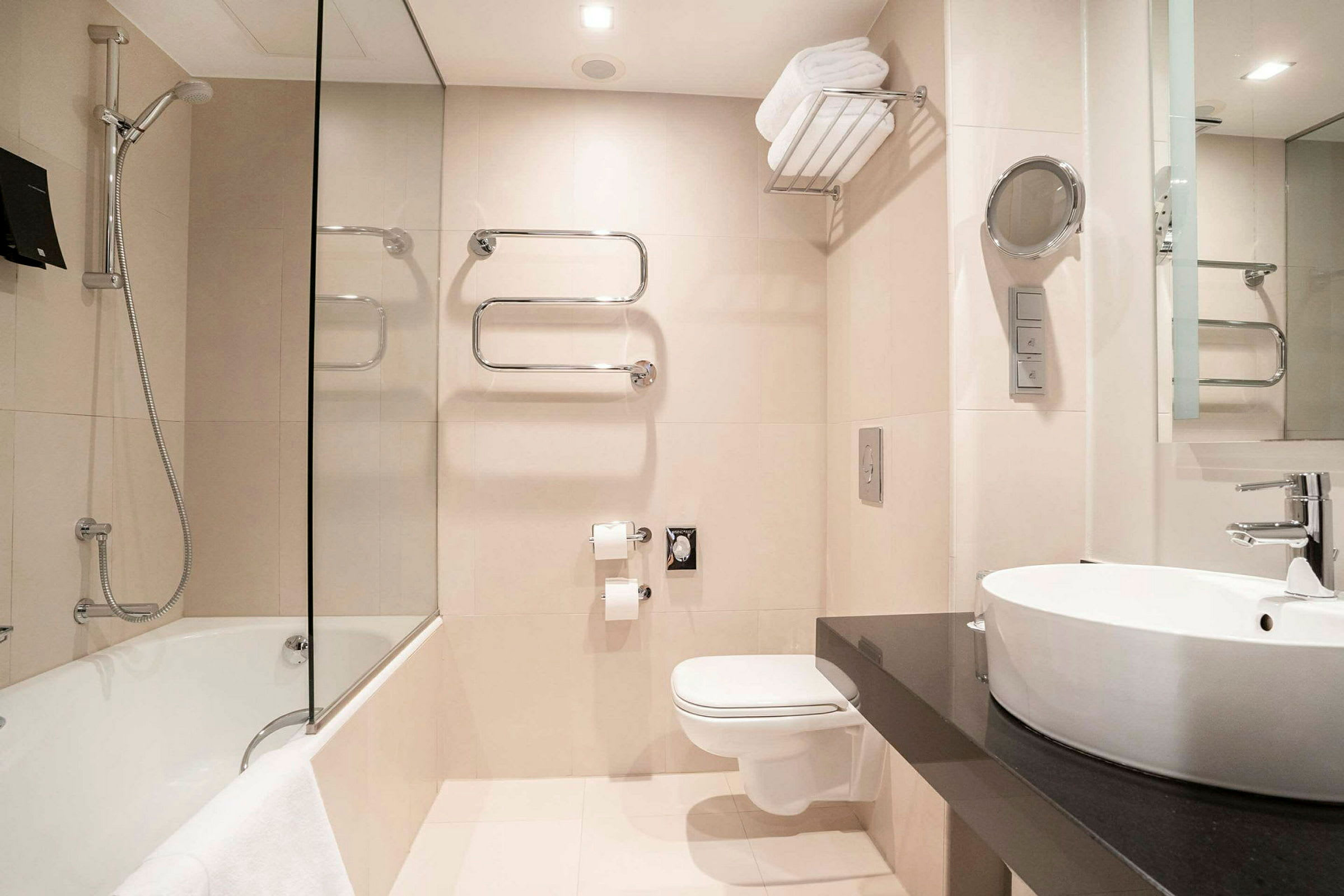 Et moderne badeværelse med badekar, vægmonteret toilet og håndvask med spejl. (AI-genereret tekst)