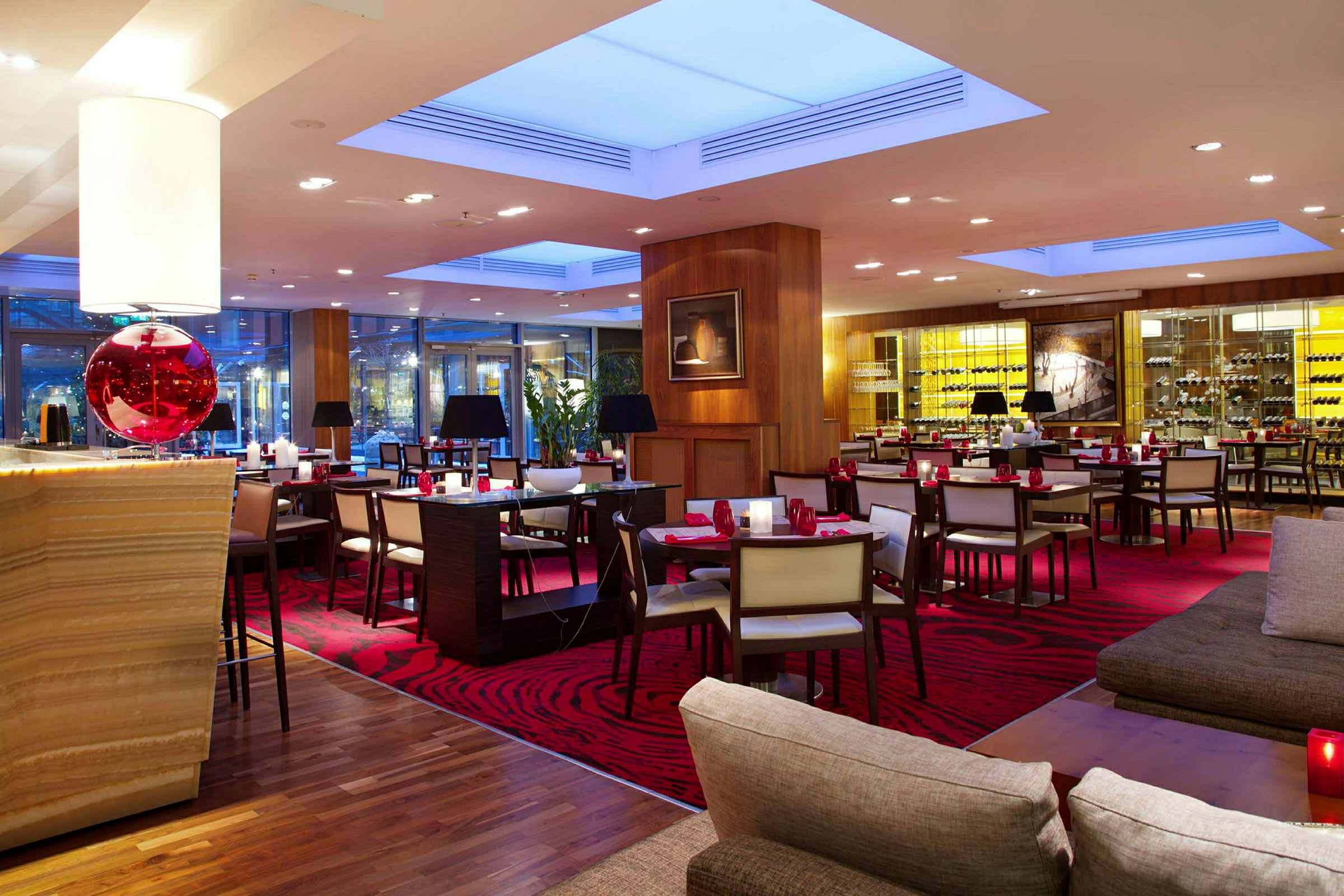 En elegant restaurant med røde tæpper og moderne indretning, med borde, stole og en afslappet atmosfære. (AI-genereret tekst)