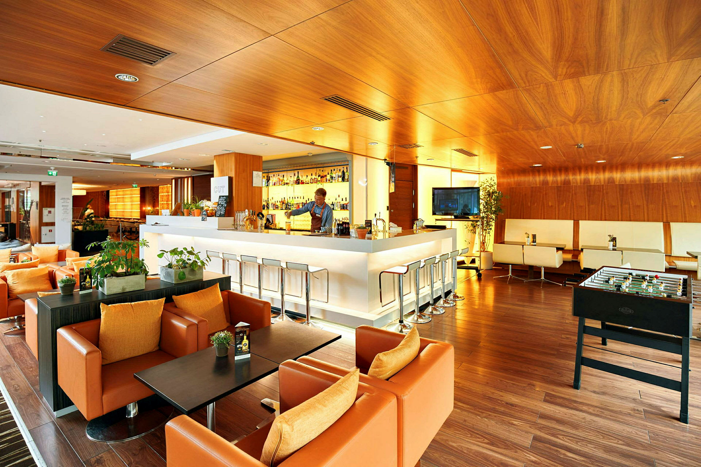 En moderne lounge med en bar, siddegrupper og et bordfodboldspil. (AI-genereret tekst)