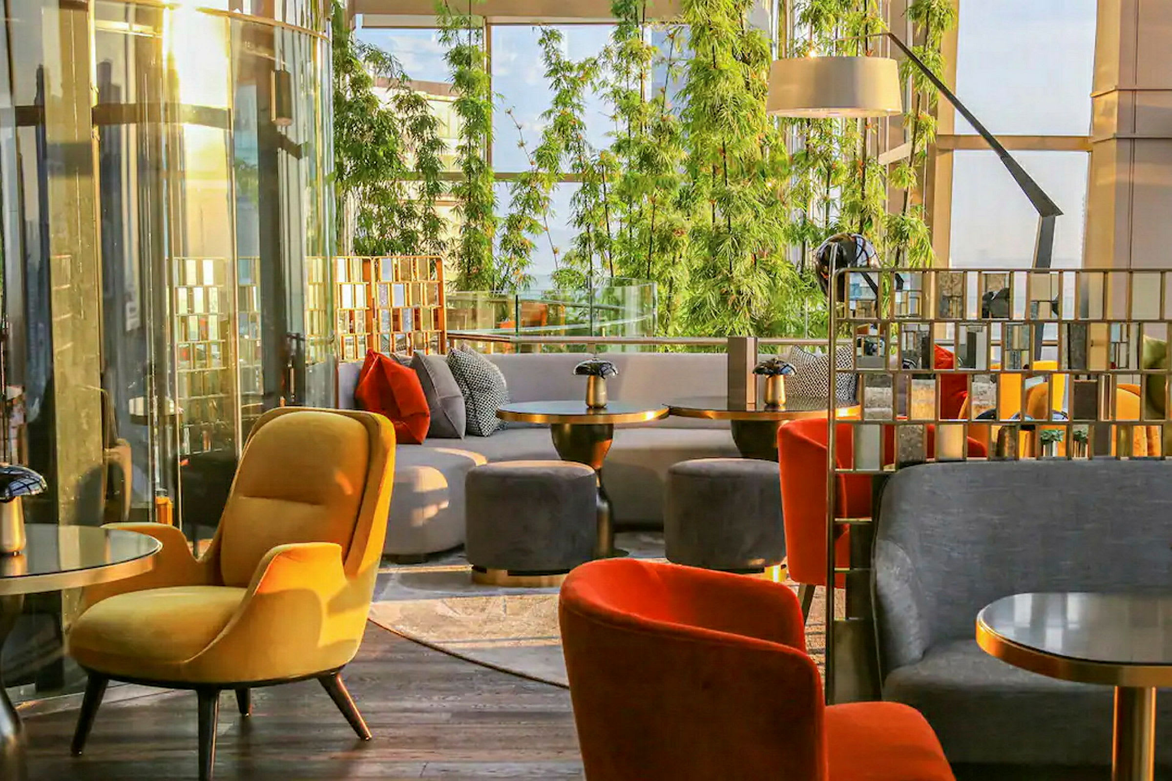 Siddeområde i moderne miljø med farverige lænestole og sofaer, grøn beplantning i baggrunden. (AI-genereret tekst)