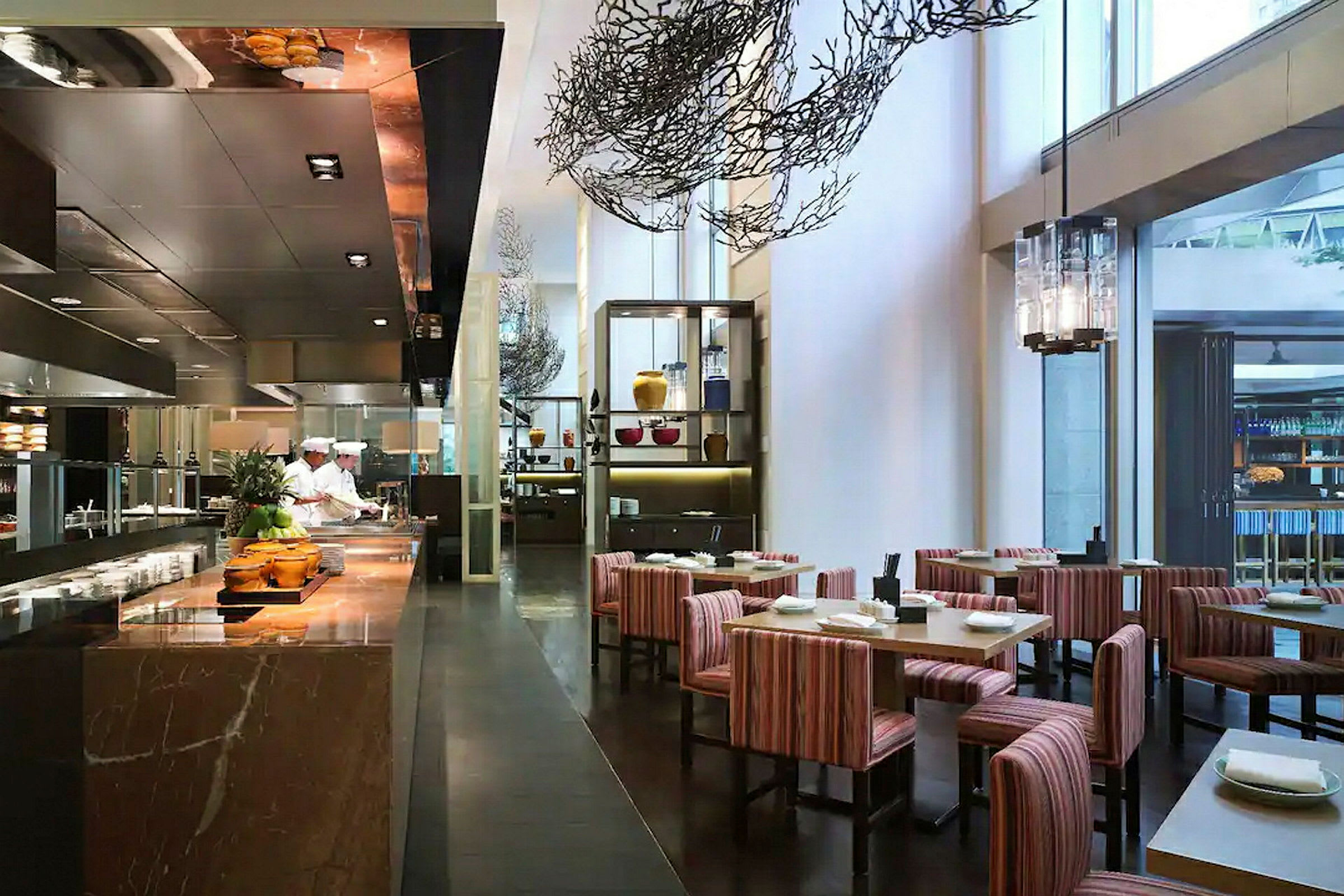 Restaurantmiljø med køkkenbord til venstre og siddepladser med borde og stole til højre. (AI-genereret tekst)