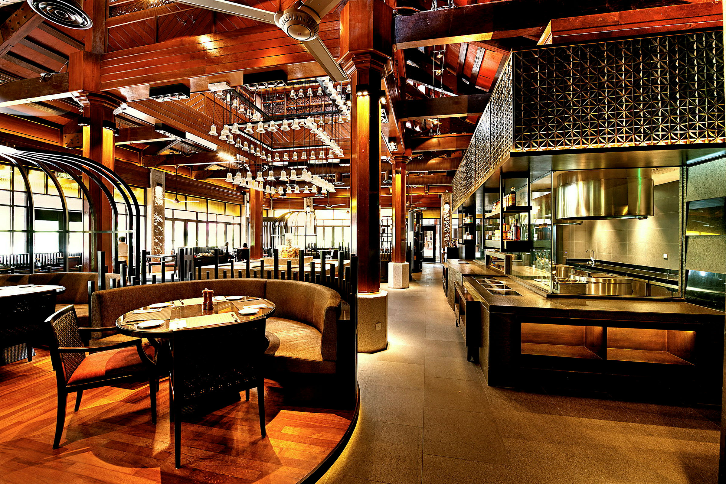 En elegant restaurantindretning med trædetaljer, runde siddegrupper og et åbent køkken med moderne design. (AI-genereret tekst)