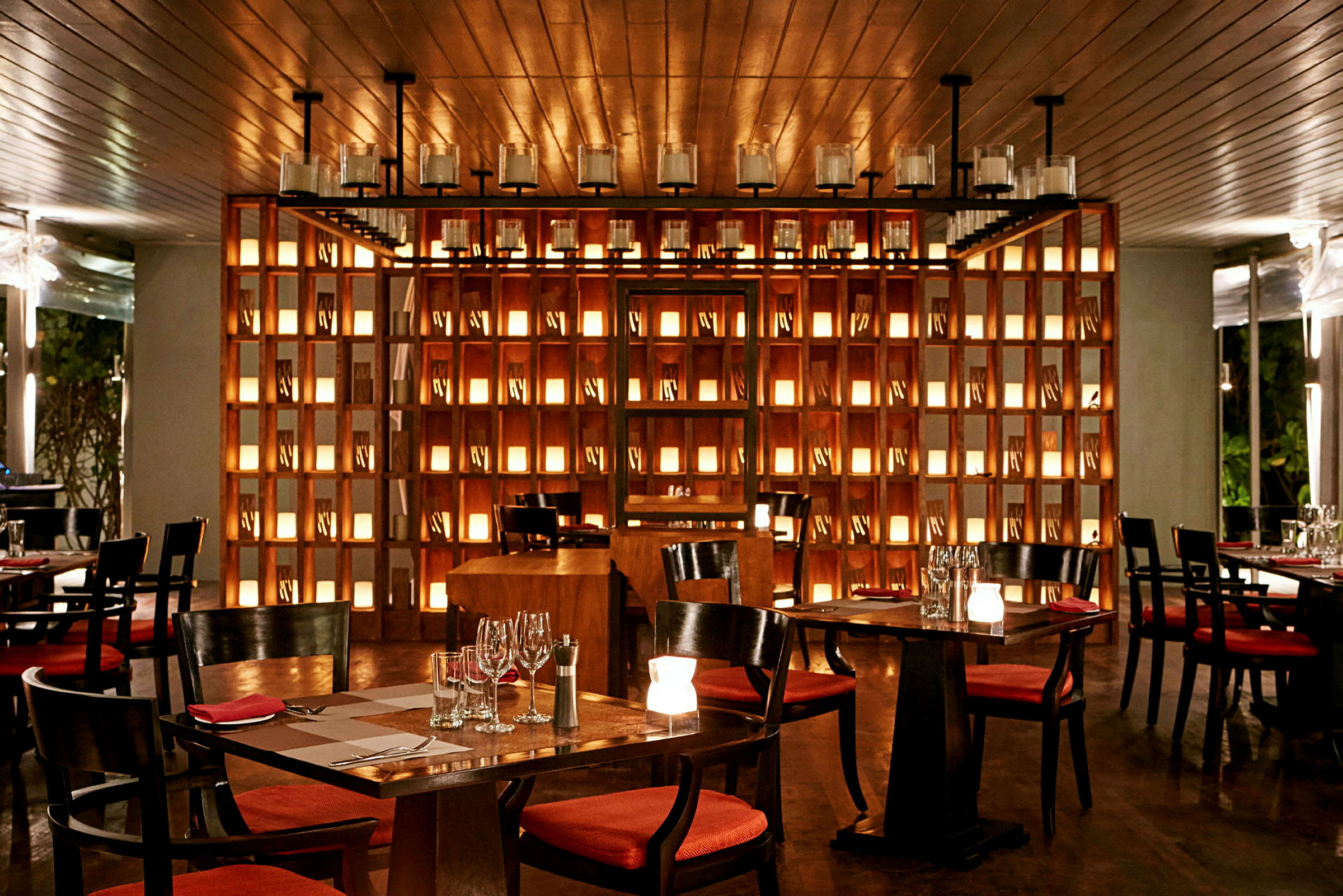 En elegant restaurantindretning med borde og stole, omgivet af blød belysning og oplyste hylder. (AI-genereret tekst)