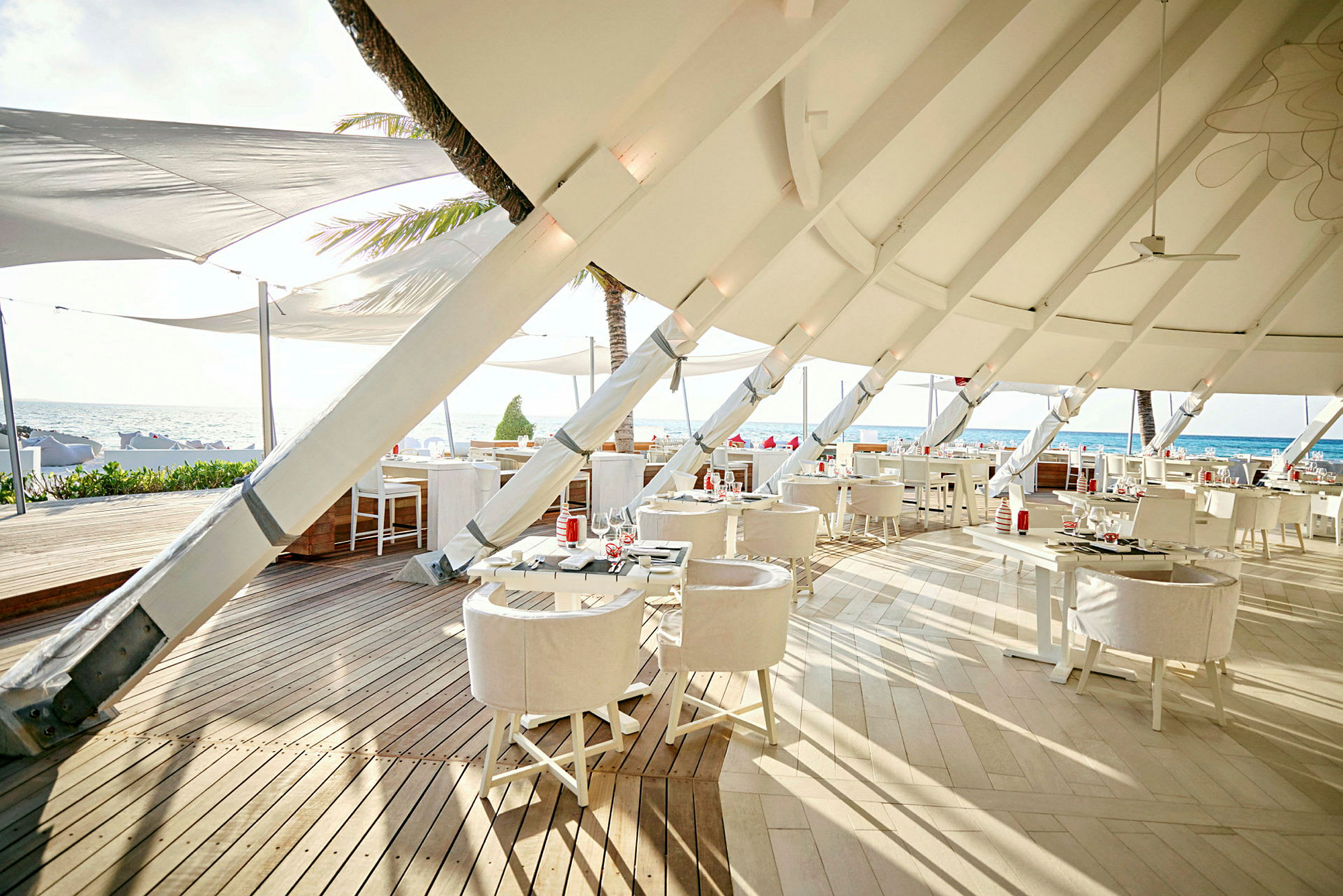 Restaurant med moderne hvide møbler og loftdug ved stranden. (AI-genereret tekst)