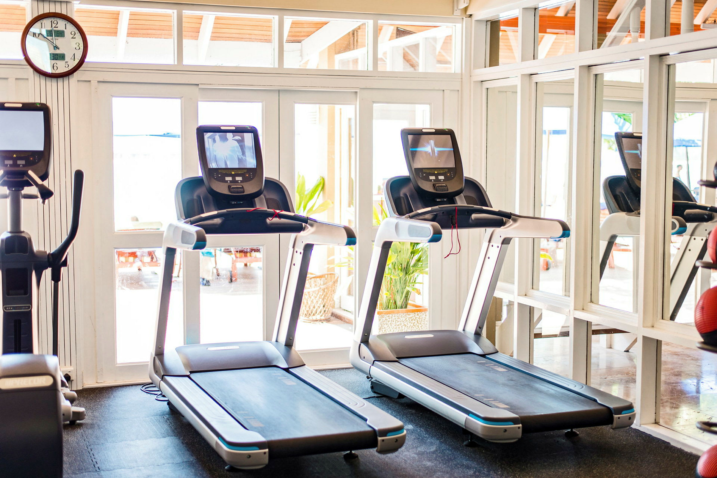 To løbebånd i et lyst fitnessrum med spejl på væggen. (AI-genereret tekst)