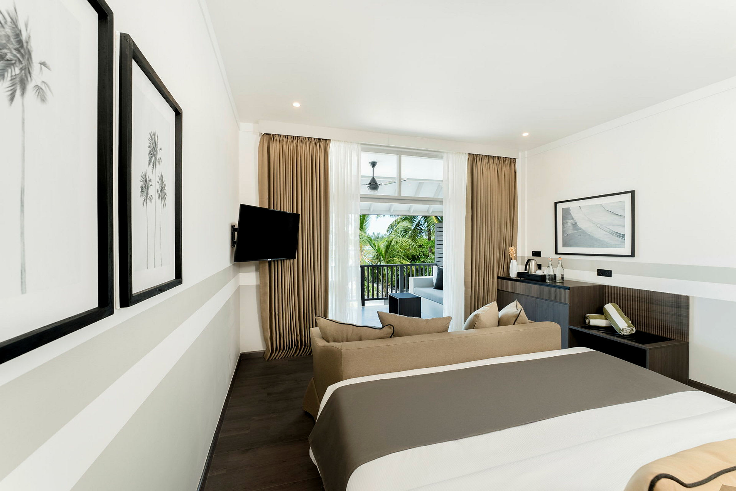 Et moderne hotelværelse med en dobbeltseng, sofa og balkon med udsigt. (AI-genereret tekst)