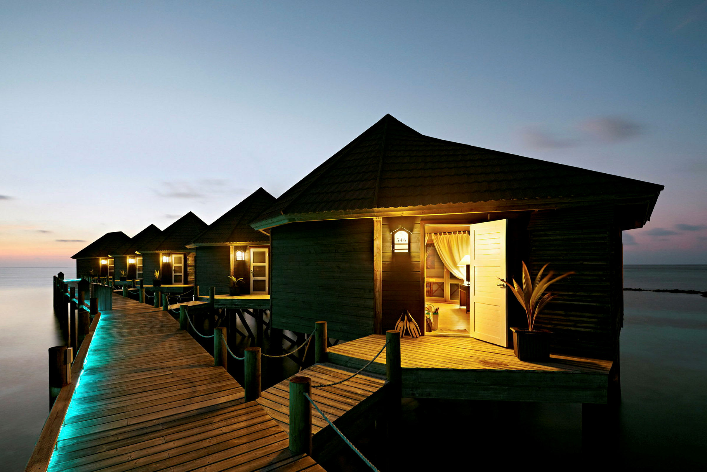 Søbungalower på en moler med aftensbelysning. (AI-genereret tekst)