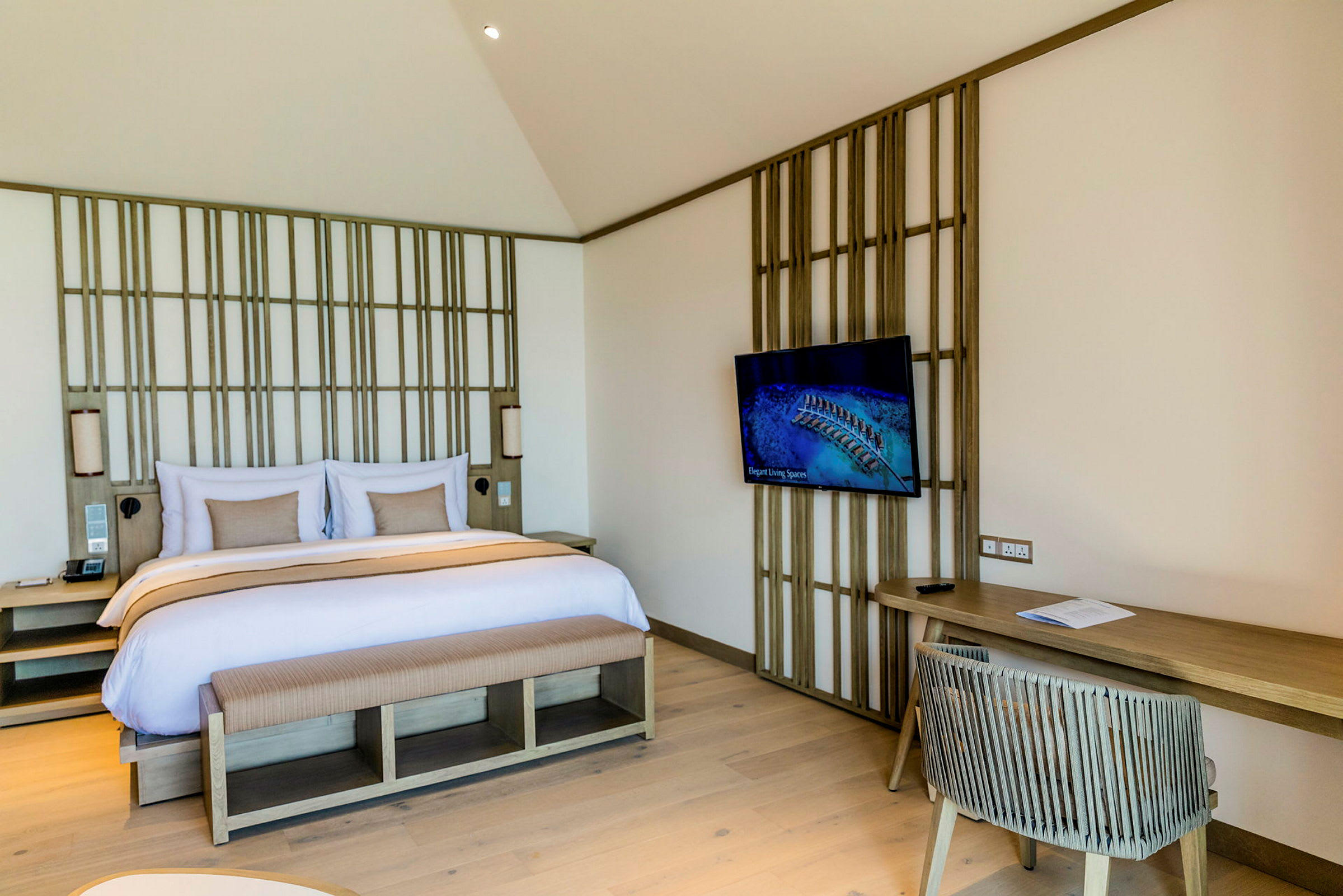 Et hotelværelse med en dobbeltseng, tv på væggen og skrivebord med stol. (AI-genereret tekst)