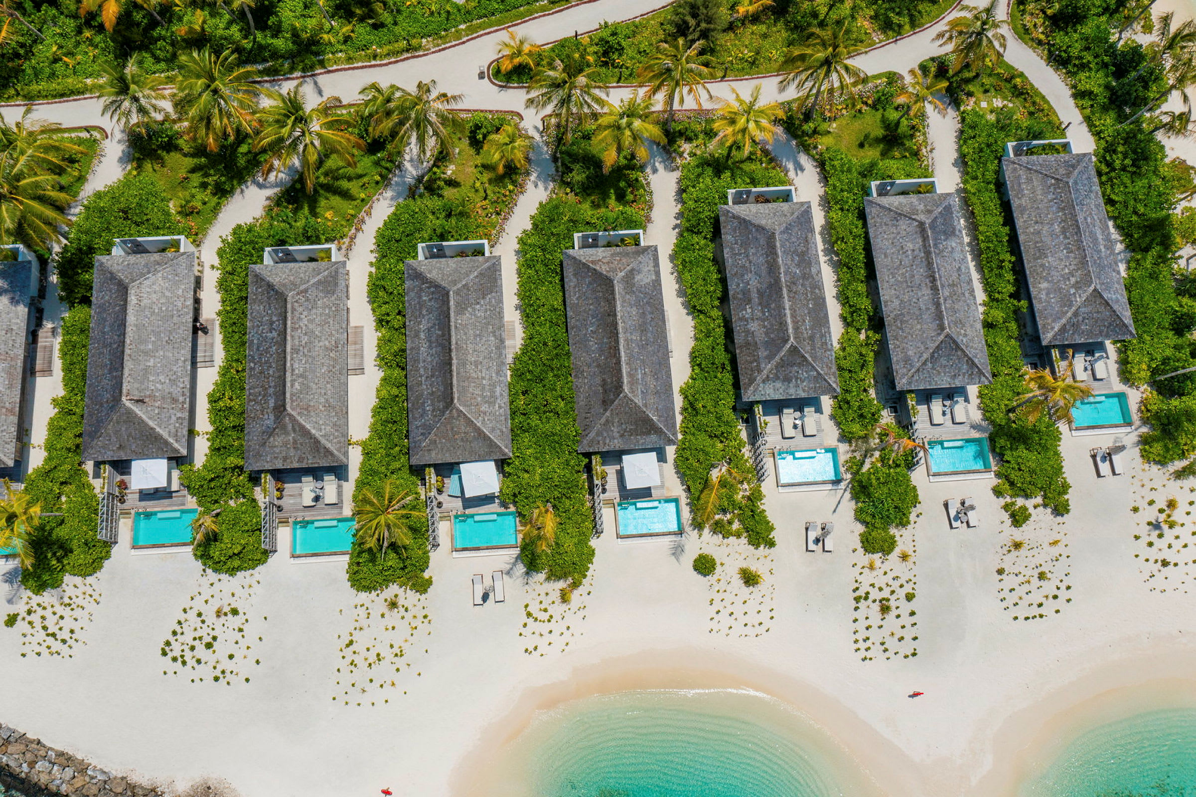 Luftfoto af strandvillaer med private pools og haver på en sandstrand ved havet. (AI-genereret tekst)