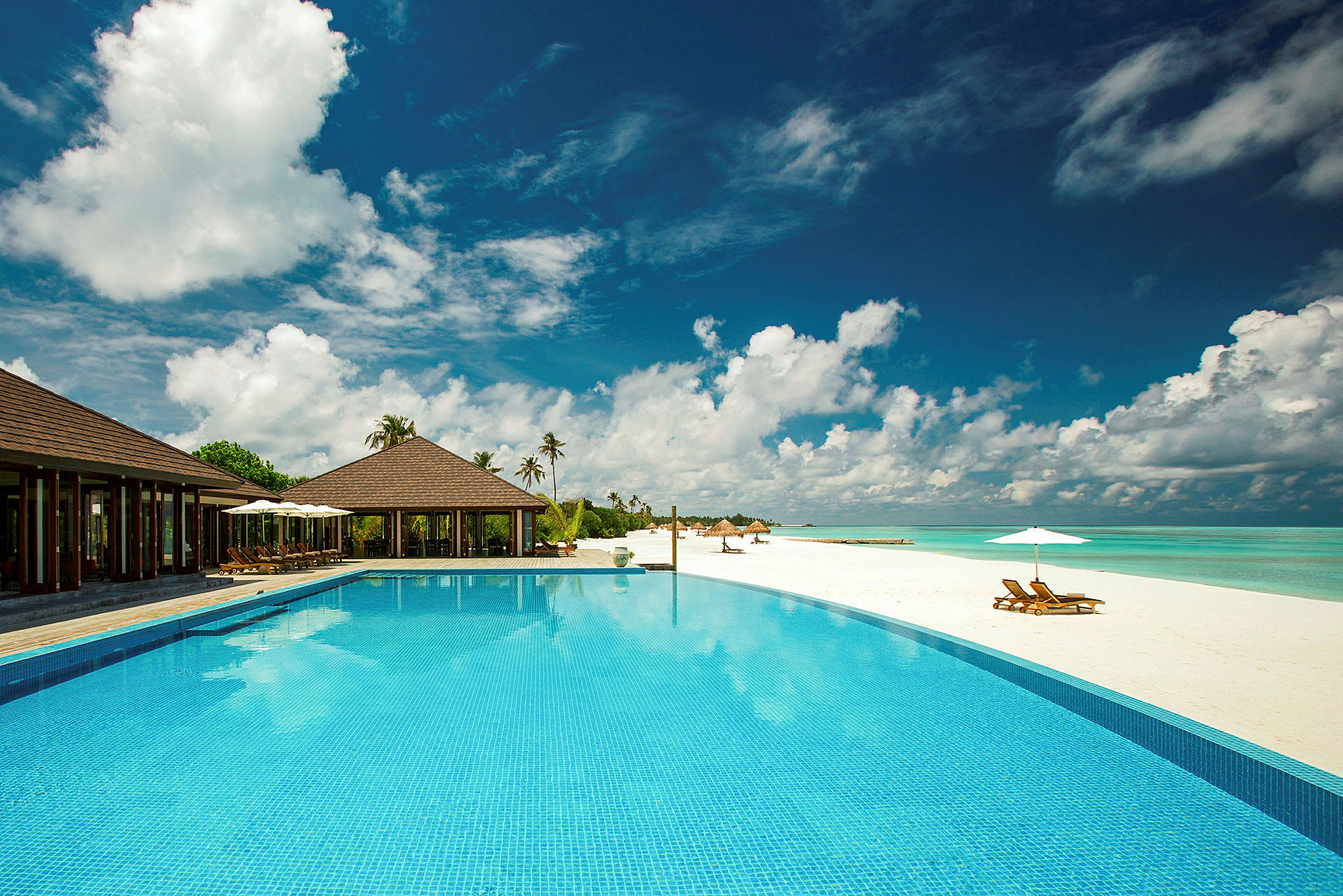 En luksuriøs resort med pool ved siden af en hvid sandstrand. (AI-genereret tekst)