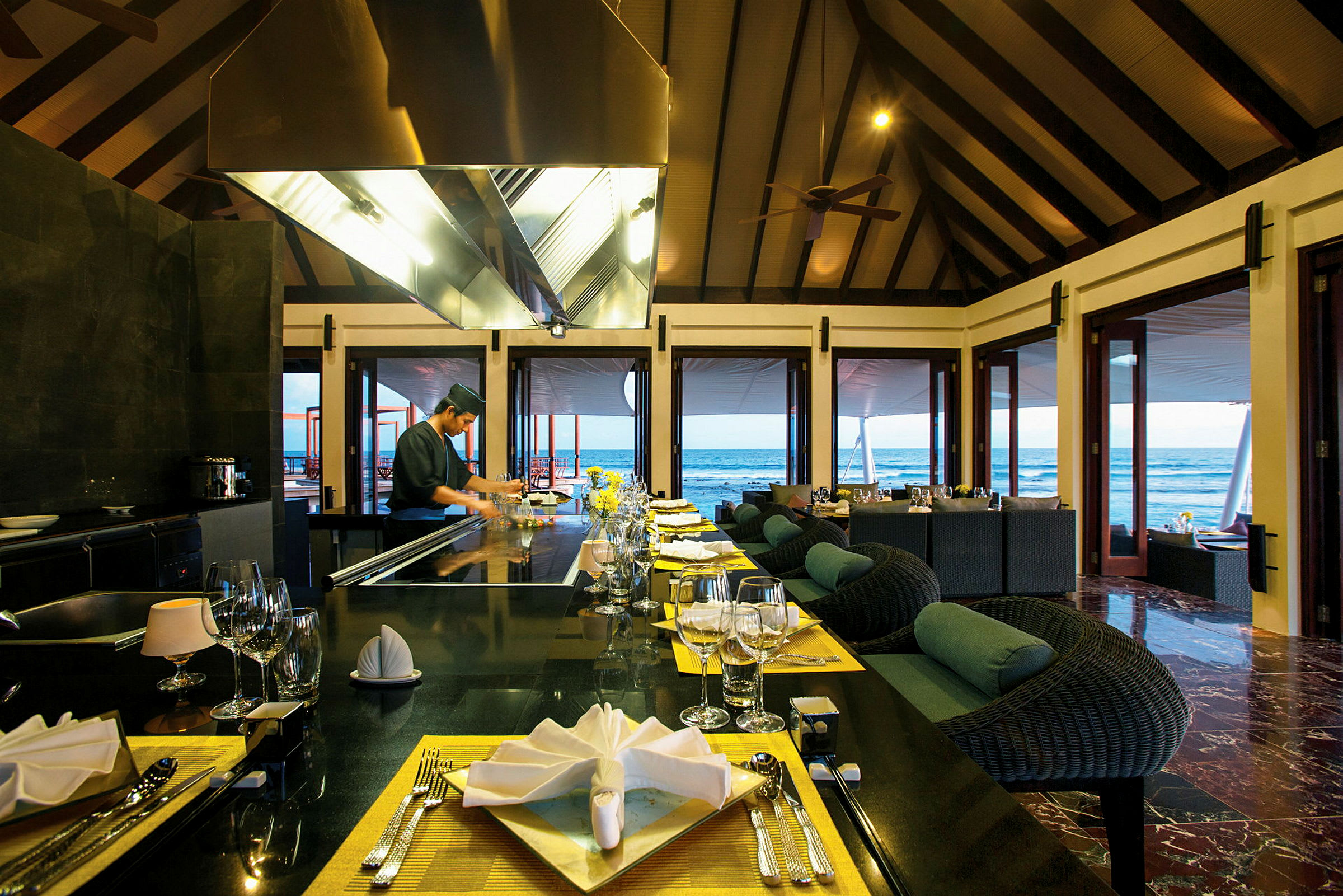 Restaurant ved havet med dækkede borde og åbne døre mod udsigten. (AI-genereret tekst)