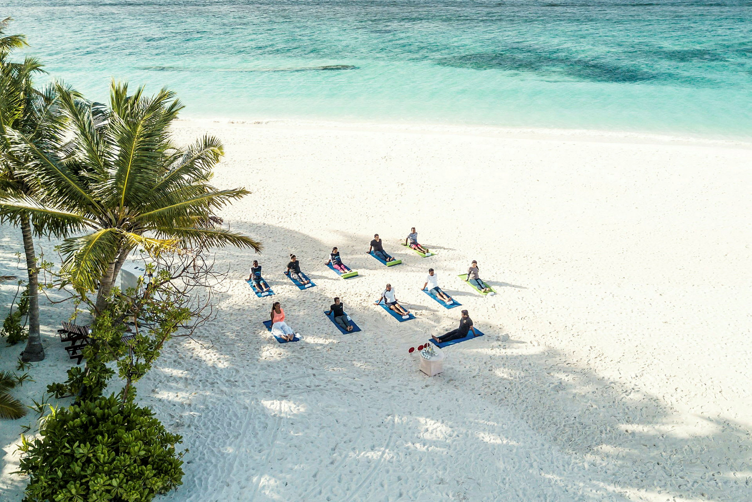 En gruppe mennesker dyrker yoga på stranden tæt ved havet. (AI-genereret tekst)