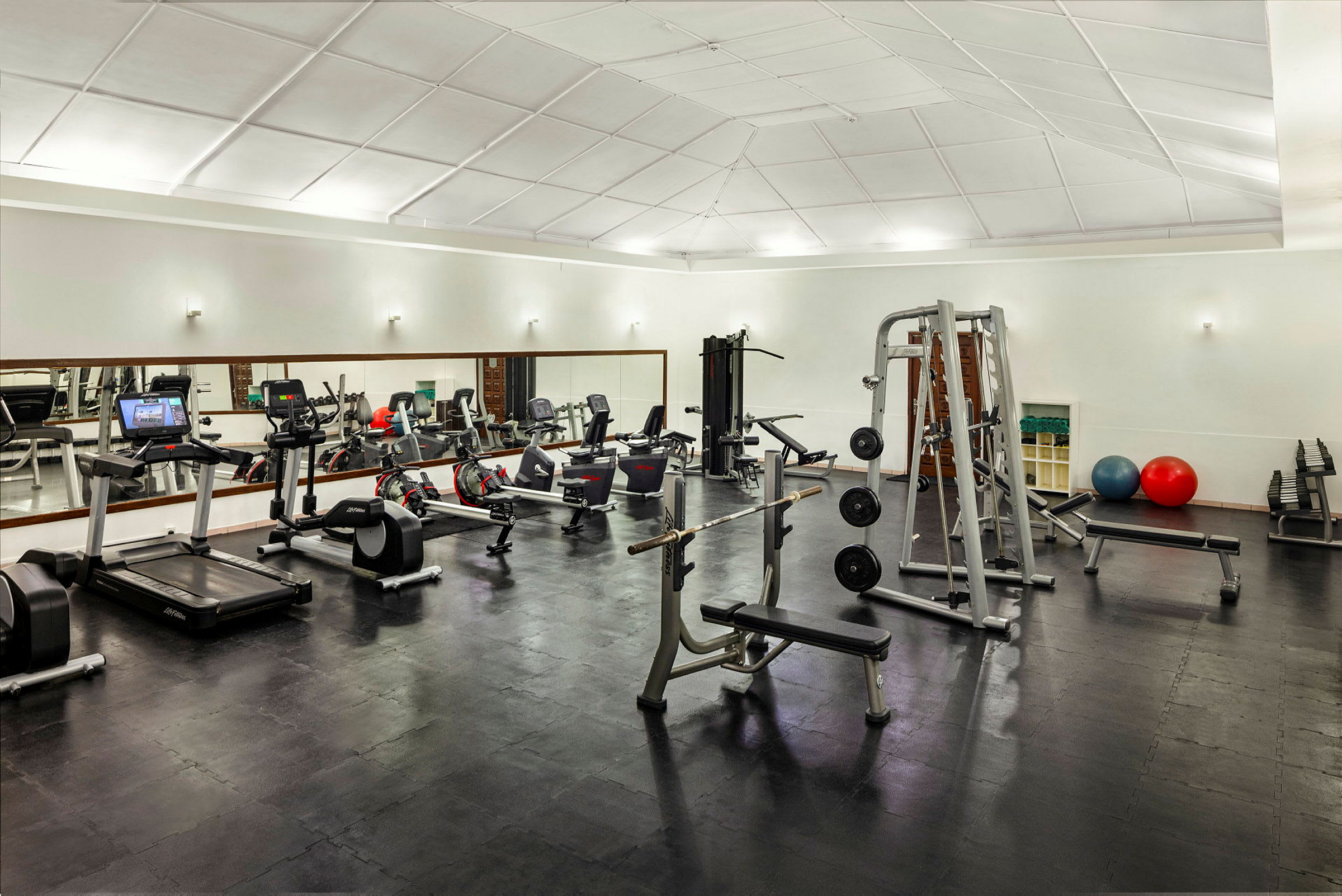 Et fitnesscenter med forskellige træningsmaskiner og udstyr, inklusive løbebånd, vægte og bænke. (AI-genereret tekst)