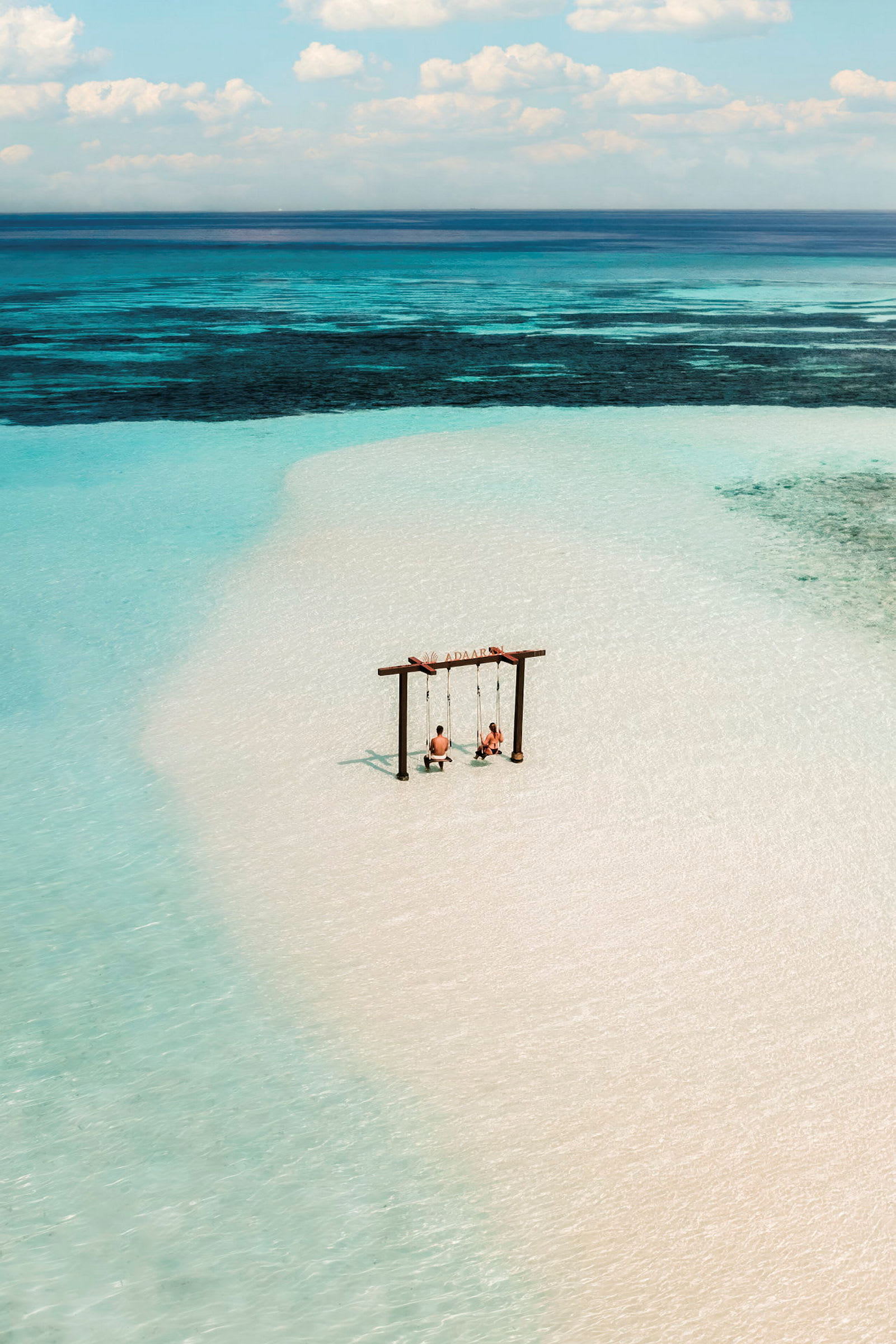To gynger står i lavt, klart vand ved en tropisk strand. (AI-genereret tekst)