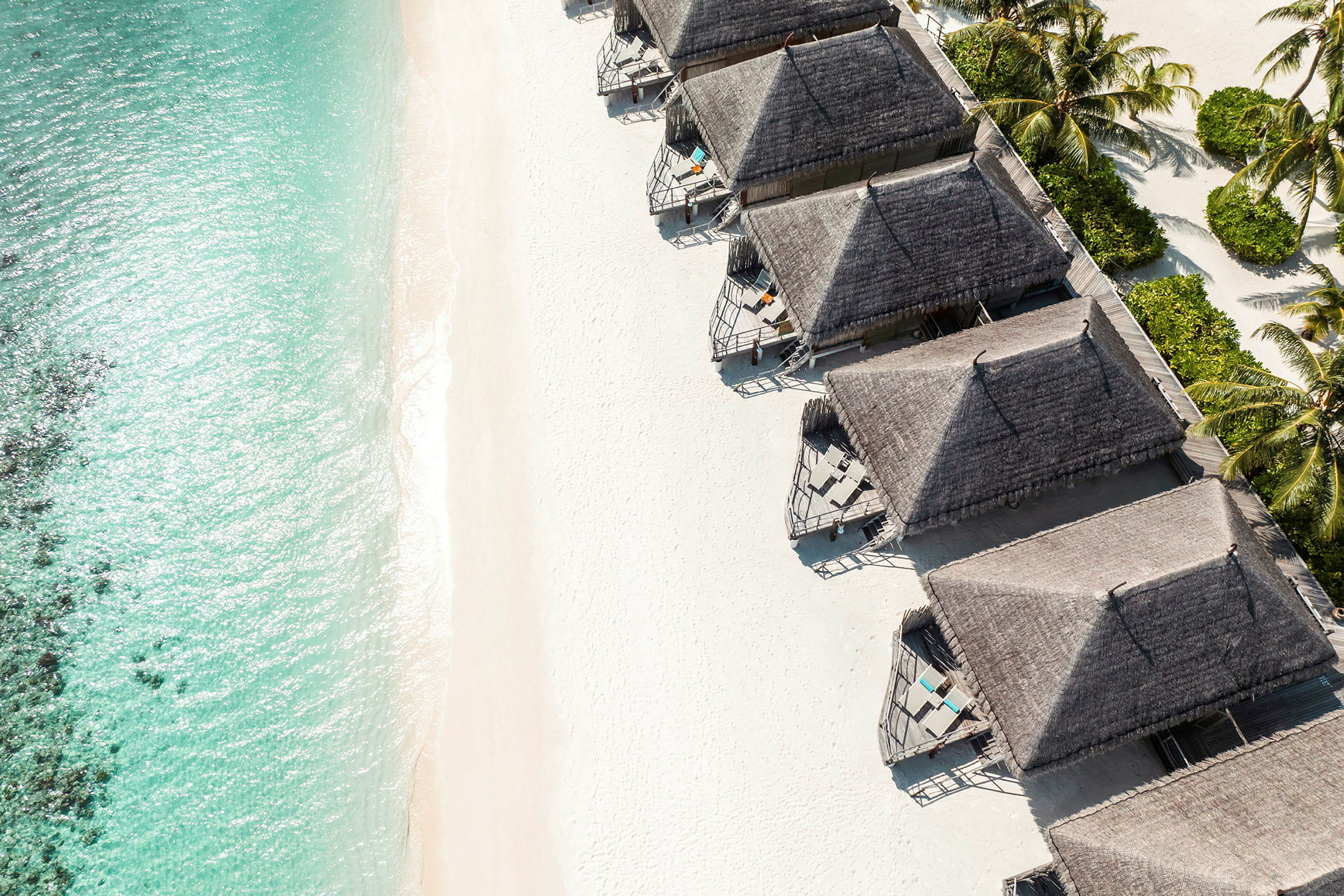 Strand med turkis vand og flere strandnære bungalows. (AI-genereret tekst)