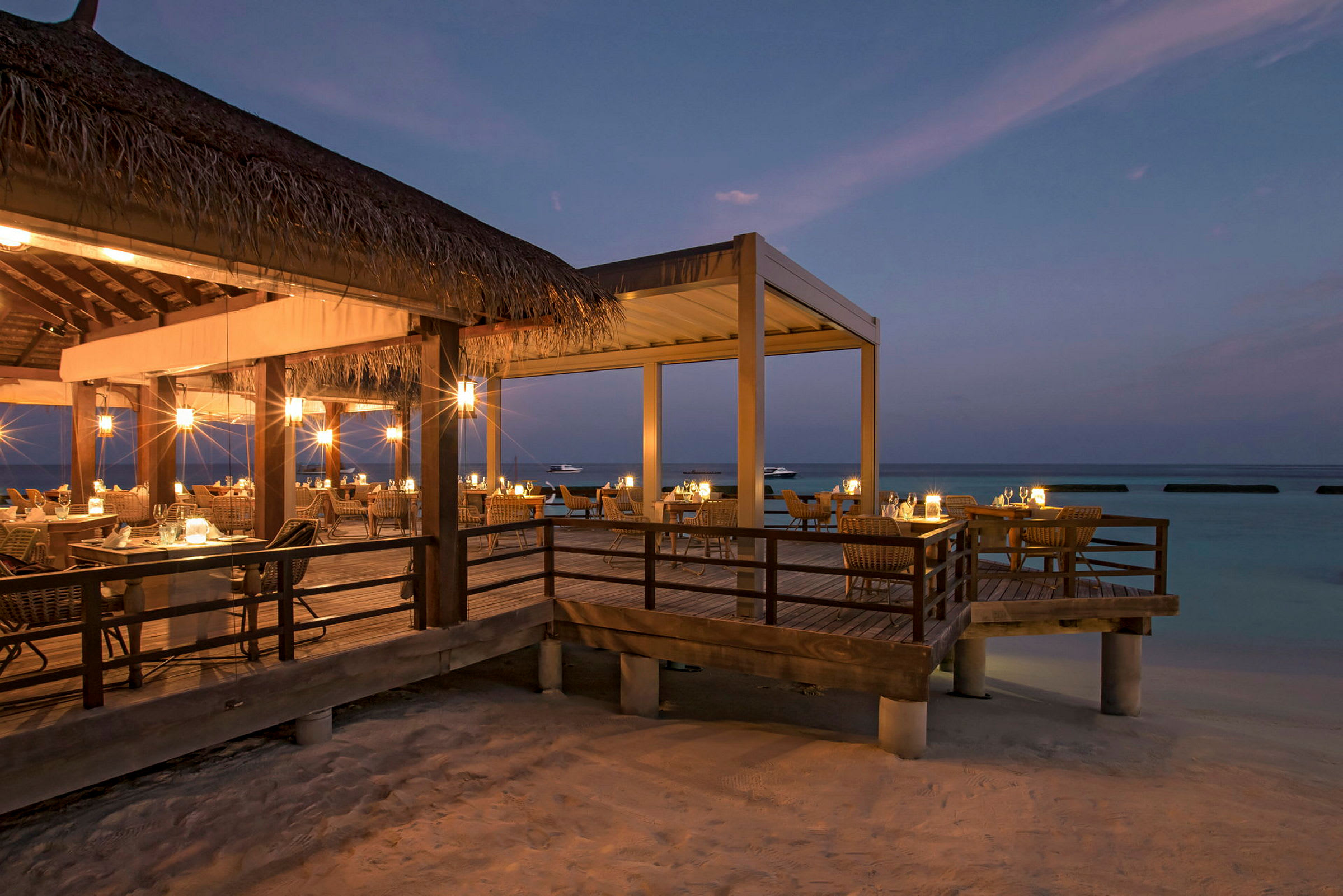 Restaurant med udendørs servering ved stranden i skumringen. (AI-genereret tekst)
