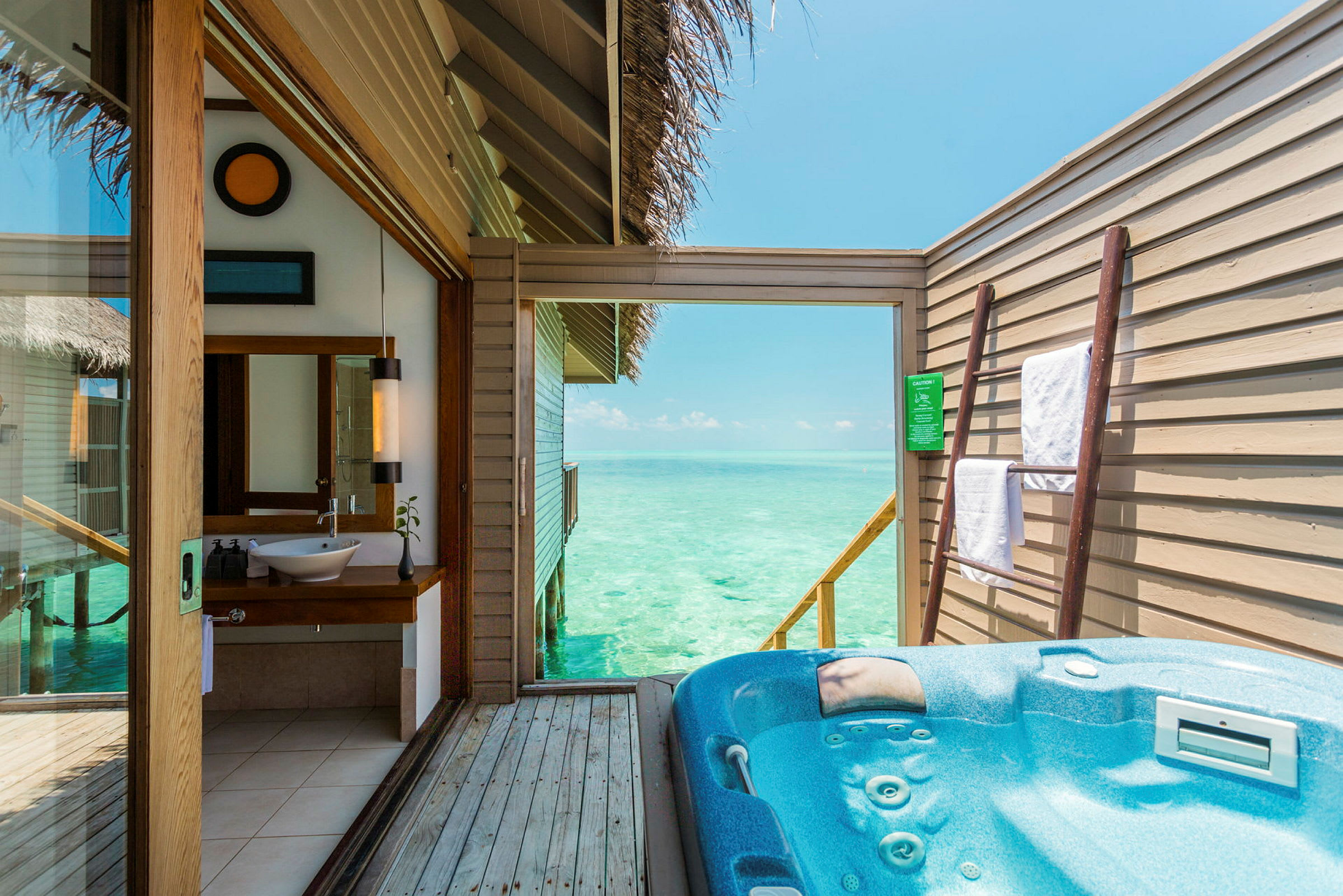 En udendørs terrasse med jacuzzi og udsigt over havet, samt interiør fra et badeværelse. (AI-genereret tekst)