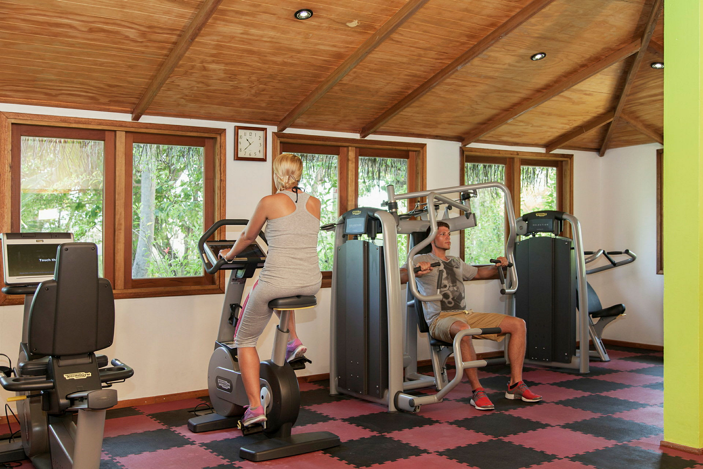 Personer der bruger træningsudstyr i et fitnesscenter. (AI-genereret tekst)