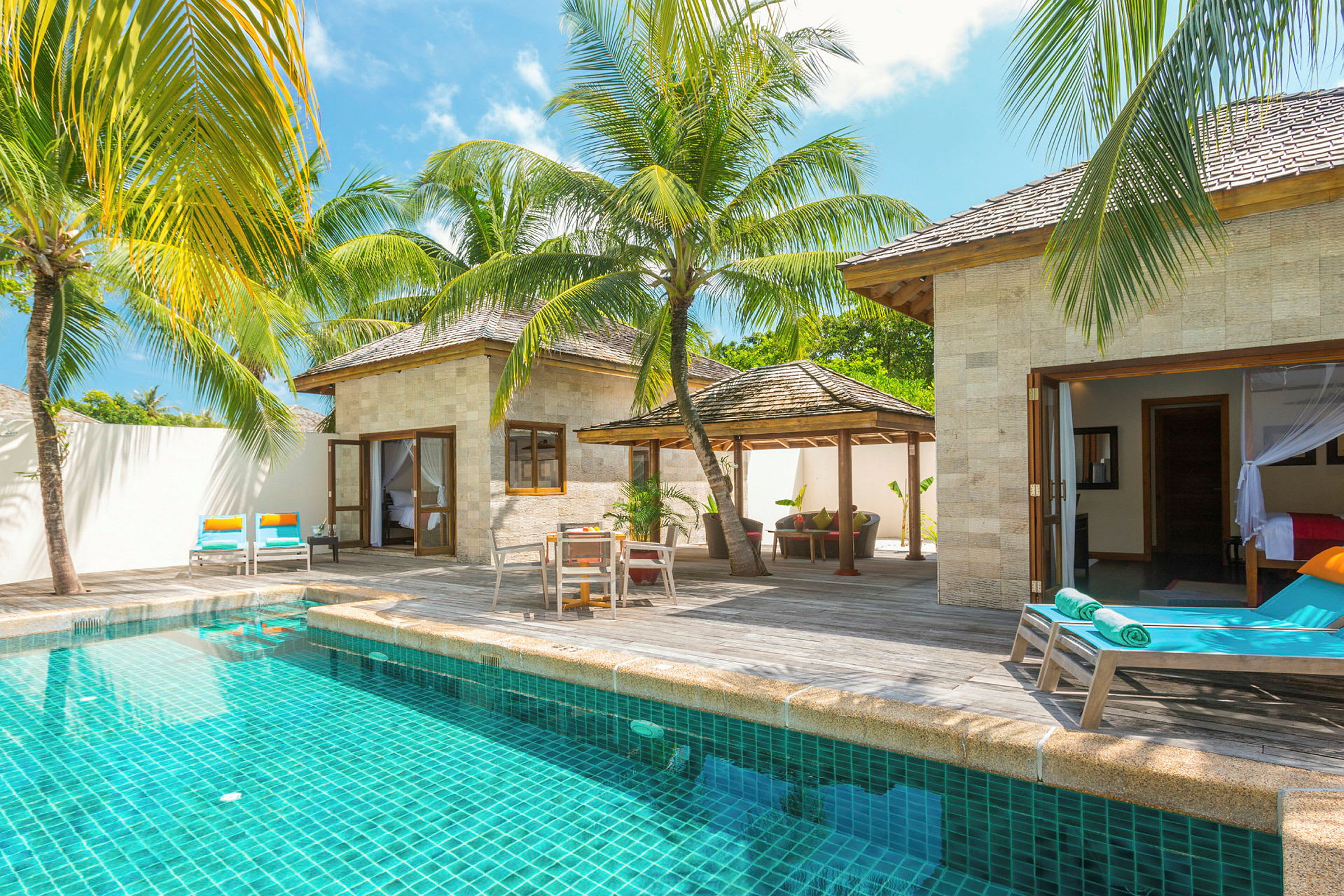 En villa med privat pool, omgivet af solsenge og tropiske palmer. (AI-genereret tekst)